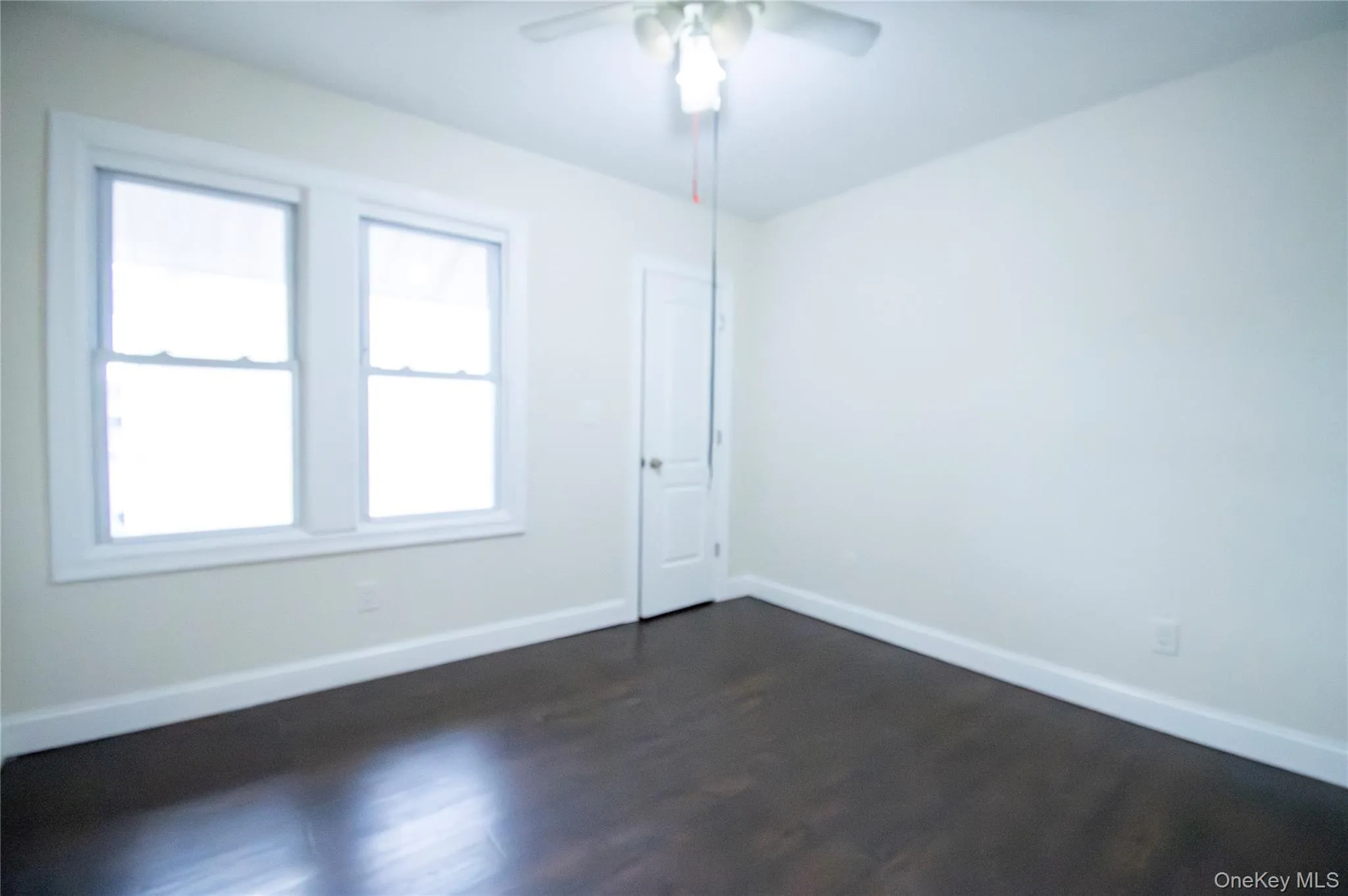 Empty room featuring dark wood-style flooring and ceiling fan Empty room featuring dark wood-style flooring and ceiling fan