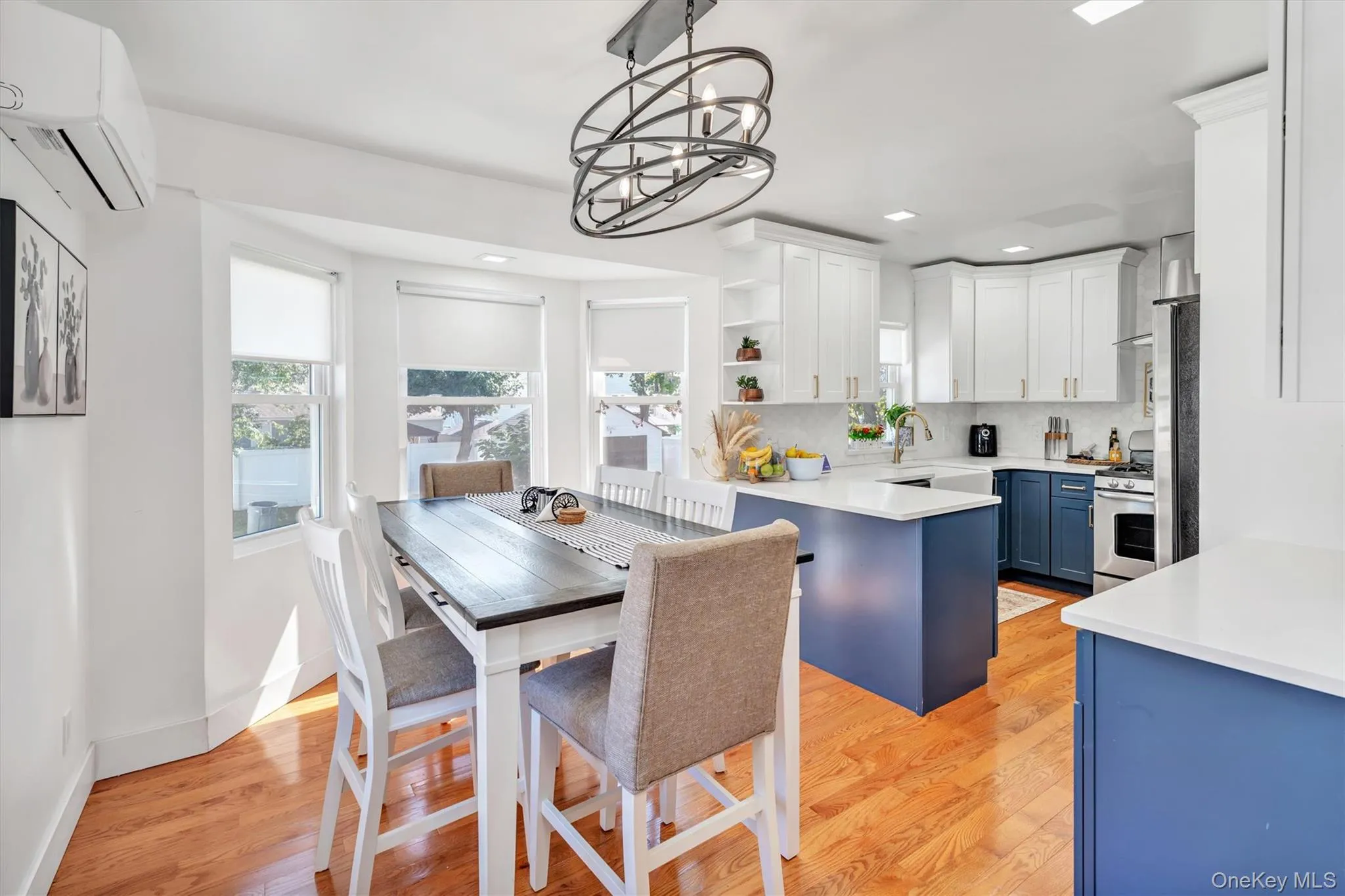 Kitchen with white cabinets, open shelves, light wood-type flooring, blue cabinets, and pendant lighting Kitchen with white cabinets, open shelves, light wood-type flooring, blue cabinets, and pendant lighting