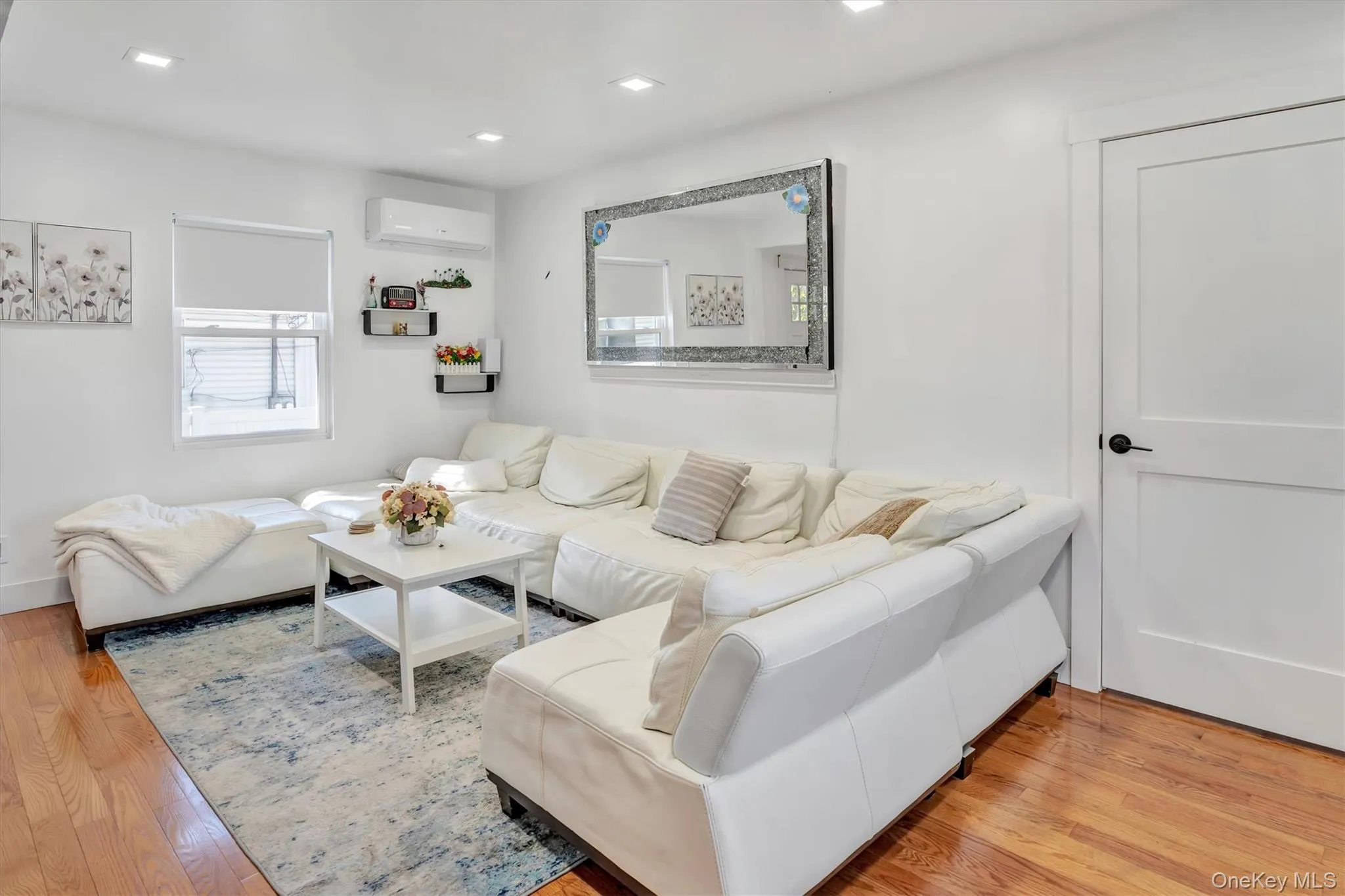 Living area featuring wood finished floors, recessed lighting, and a wall mounted AC Living area featuring wood finished floors, recessed lighting, and a wall mounted AC