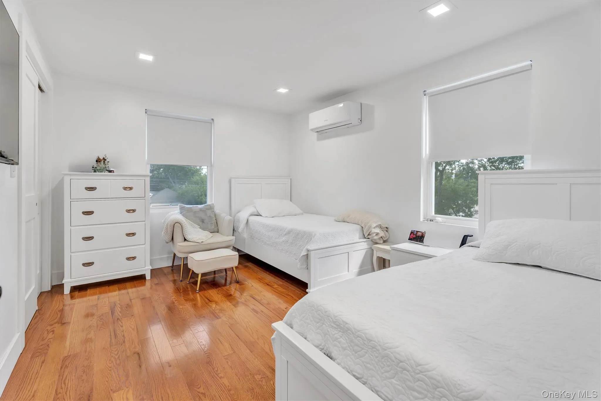 Bedroom with light wood finished floors, recessed lighting, and a wall mounted air conditioner Bedroom with light wood finished floors, recessed lighting, and a wall mounted air conditioner