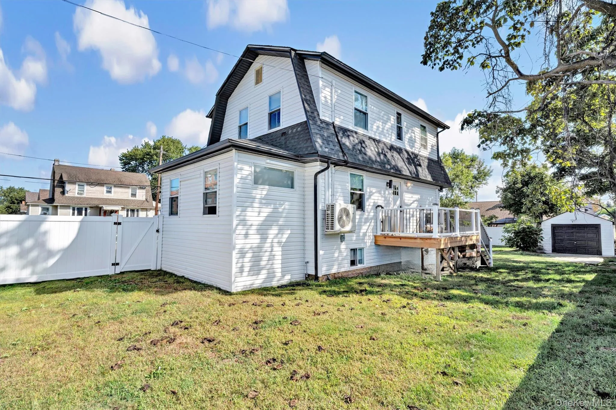 Back of property with a gambrel roof, a gate, an outbuilding, and a wooden deck Back of property with a gambrel roof, a gate, an outbuilding, and a wooden deck