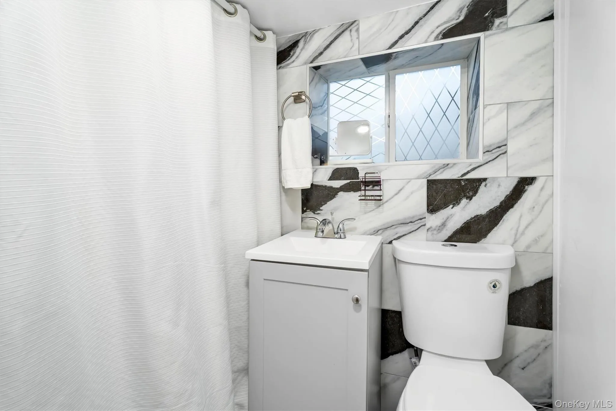 Bathroom with vanity, tile walls, and a shower with shower curtain Bathroom with vanity, tile walls, and a shower with shower curtain