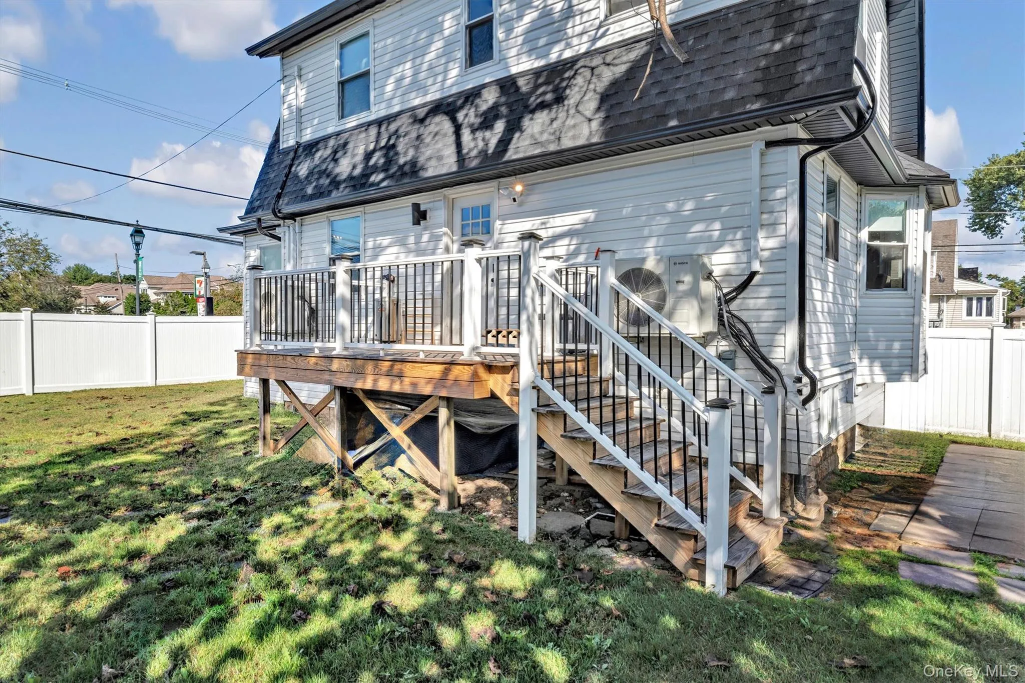 Rear view of house with a wooden deck, roof with shingles, and stairs Rear view of house with a wooden deck, roof with shingles, and stairs