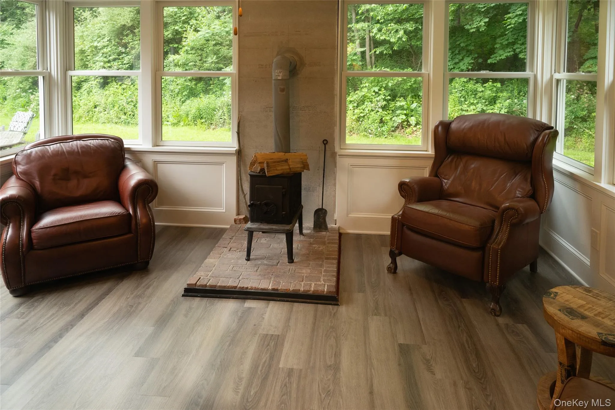 Sitting room with a wood stove, a decorative wall, and wood finished floors Sitting room with a wood stove, a decorative wall, and wood finished floors