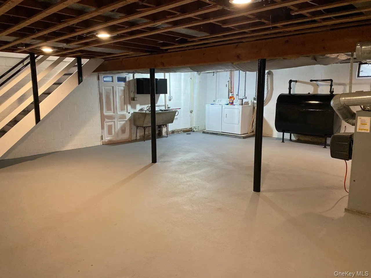 Unfinished basement featuring washing machine and dryer and oil tank Unfinished basement featuring washing machine and dryer and oil tank
