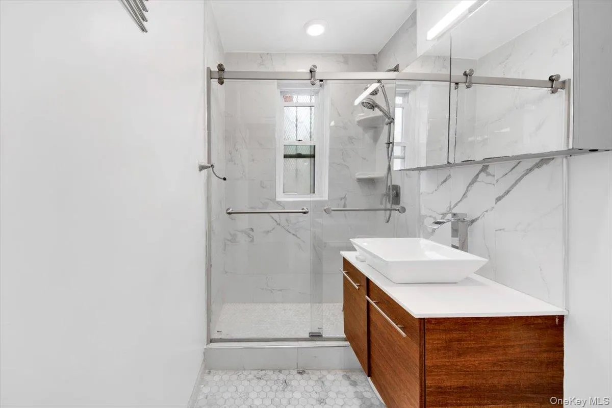 Bathroom featuring vanity and a marble finish shower Bathroom featuring vanity and a marble finish shower