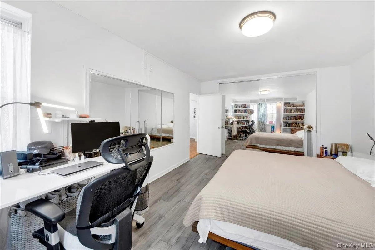 Bedroom featuring a desk, a closet, and wood finished floors Bedroom featuring a desk, a closet, and wood finished floors