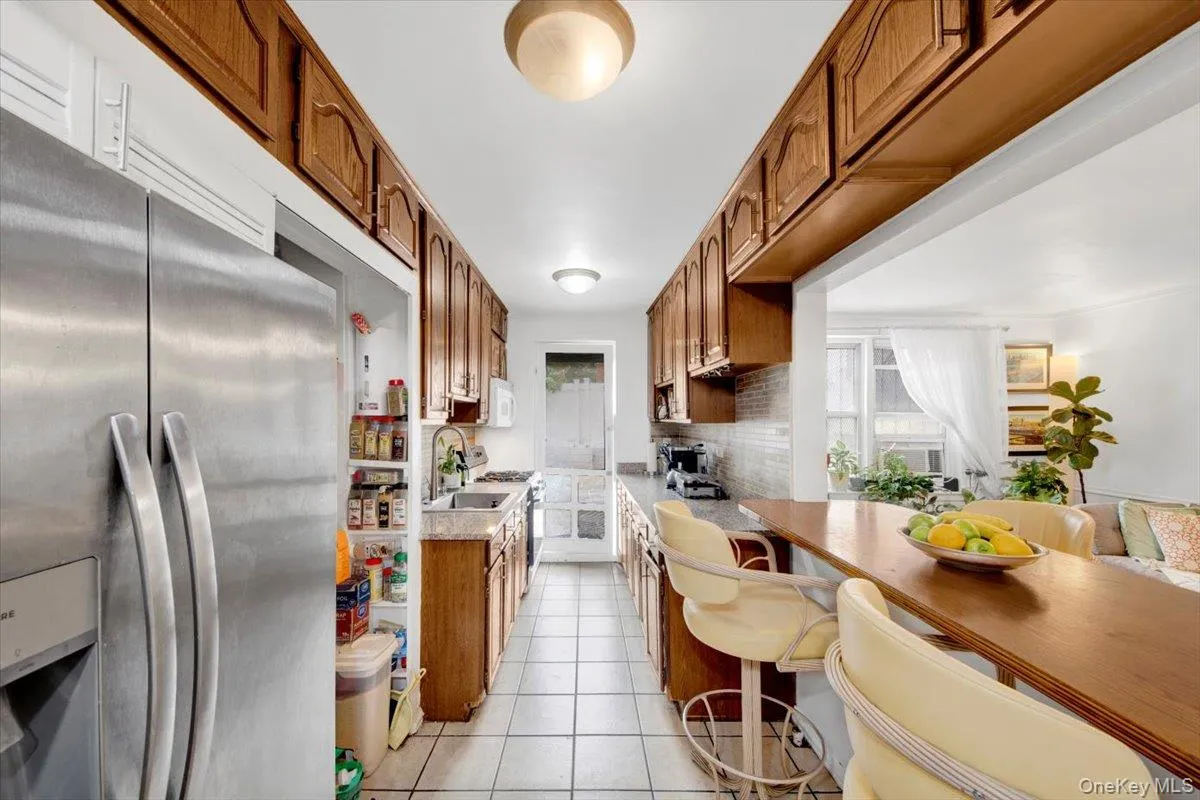 Kitchen with brown cabinets, appliances with stainless steel finishes, light countertops, light tile patterned floors, and tasteful backsplash Kitchen with brown cabinets, appliances with stainless steel finishes, light countertops, light tile patterned floors, and tasteful backsplash