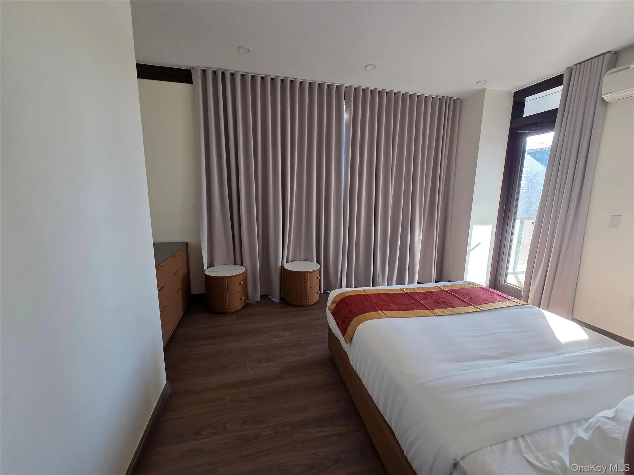 Bedroom featuring dark wood-style flooring and an AC wall unit Bedroom featuring dark wood-style flooring and an AC wall unit