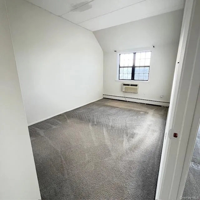 Bonus room featuring lofted ceiling, carpet flooring, baseboard heating, and an AC wall unit Bonus room featuring lofted ceiling, carpet flooring, baseboard heating, and an AC wall unit
