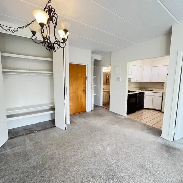 Unfurnished dining area featuring light colored carpet and a chandelier Unfurnished dining area featuring light colored carpet and a chandelier
