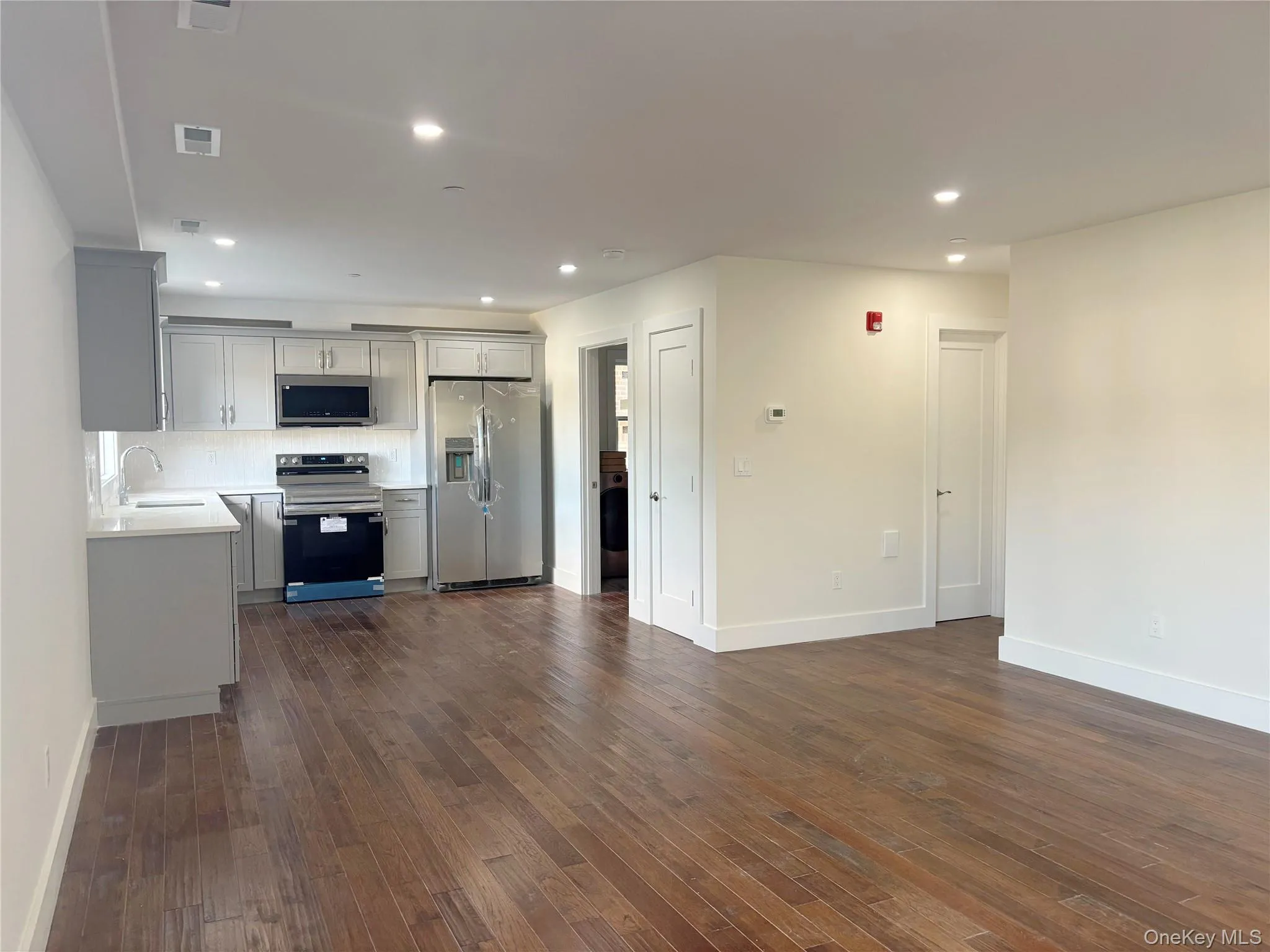Kitchen featuring stainless steel appliances, gray cabinets, dark wood-style flooring, recessed lighting, and decorative backsplash Kitchen featuring stainless steel appliances, gray cabinets, dark wood-style flooring, recessed lighting, and decorative backsplash
