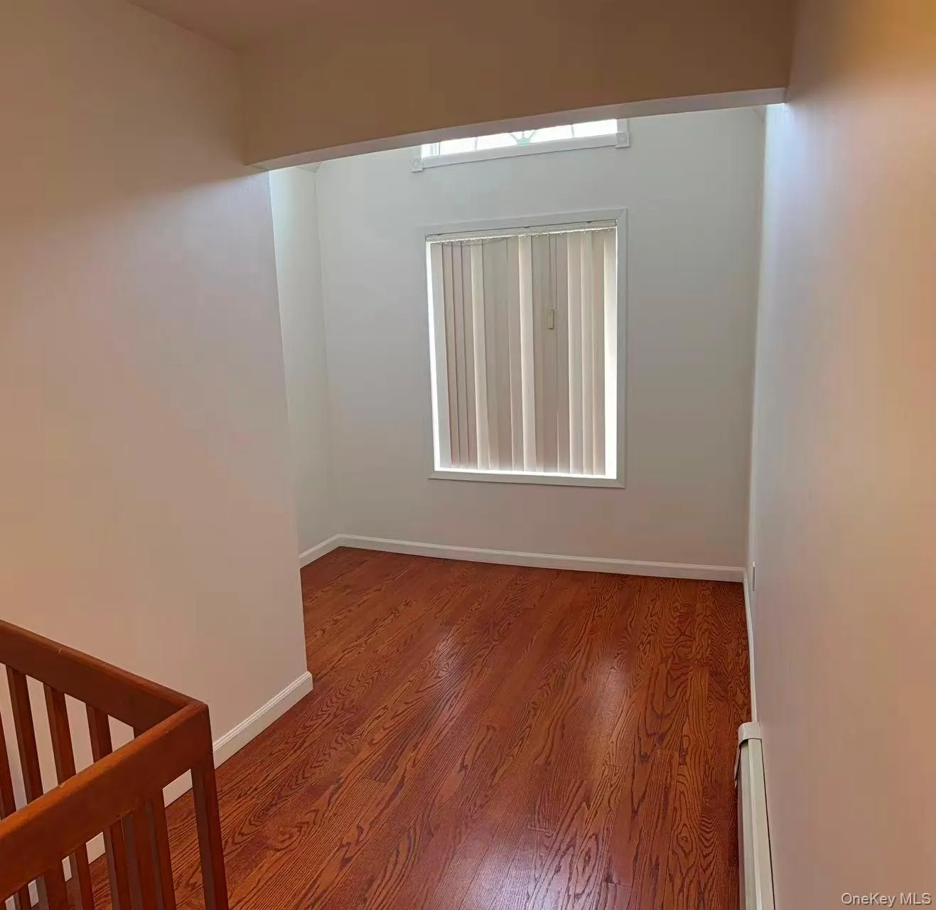Empty room with healthy amount of natural light, wood finished floors, and baseboard heating Empty room with healthy amount of natural light, wood finished floors, and baseboard heating