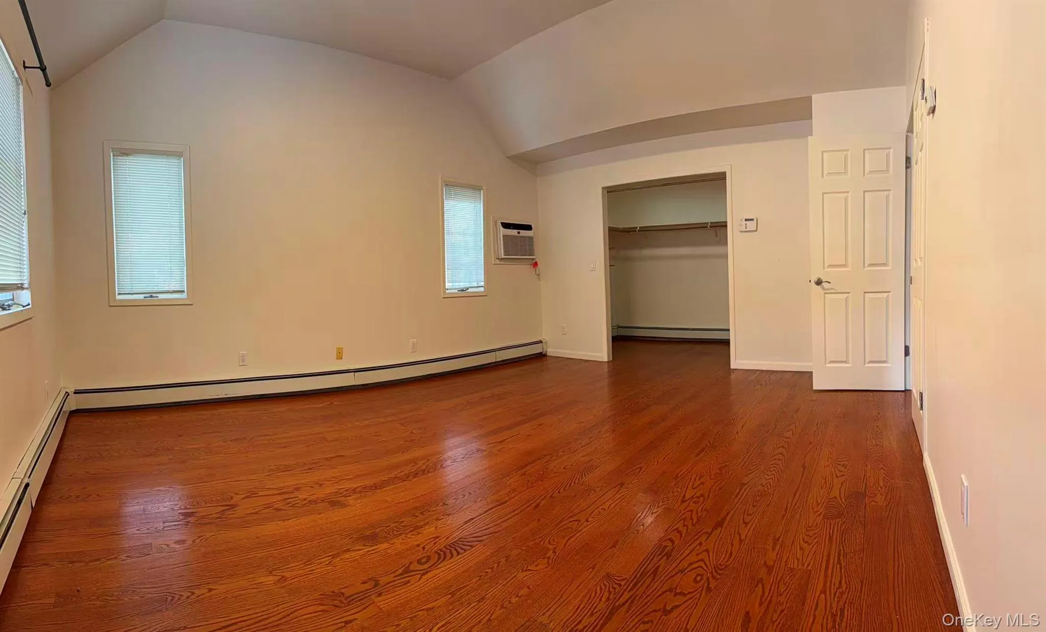 Unfurnished bedroom with a baseboard heating unit, lofted ceiling, a closet, and dark wood finished floors Unfurnished bedroom with a baseboard heating unit, lofted ceiling, a closet, and dark wood finished floors