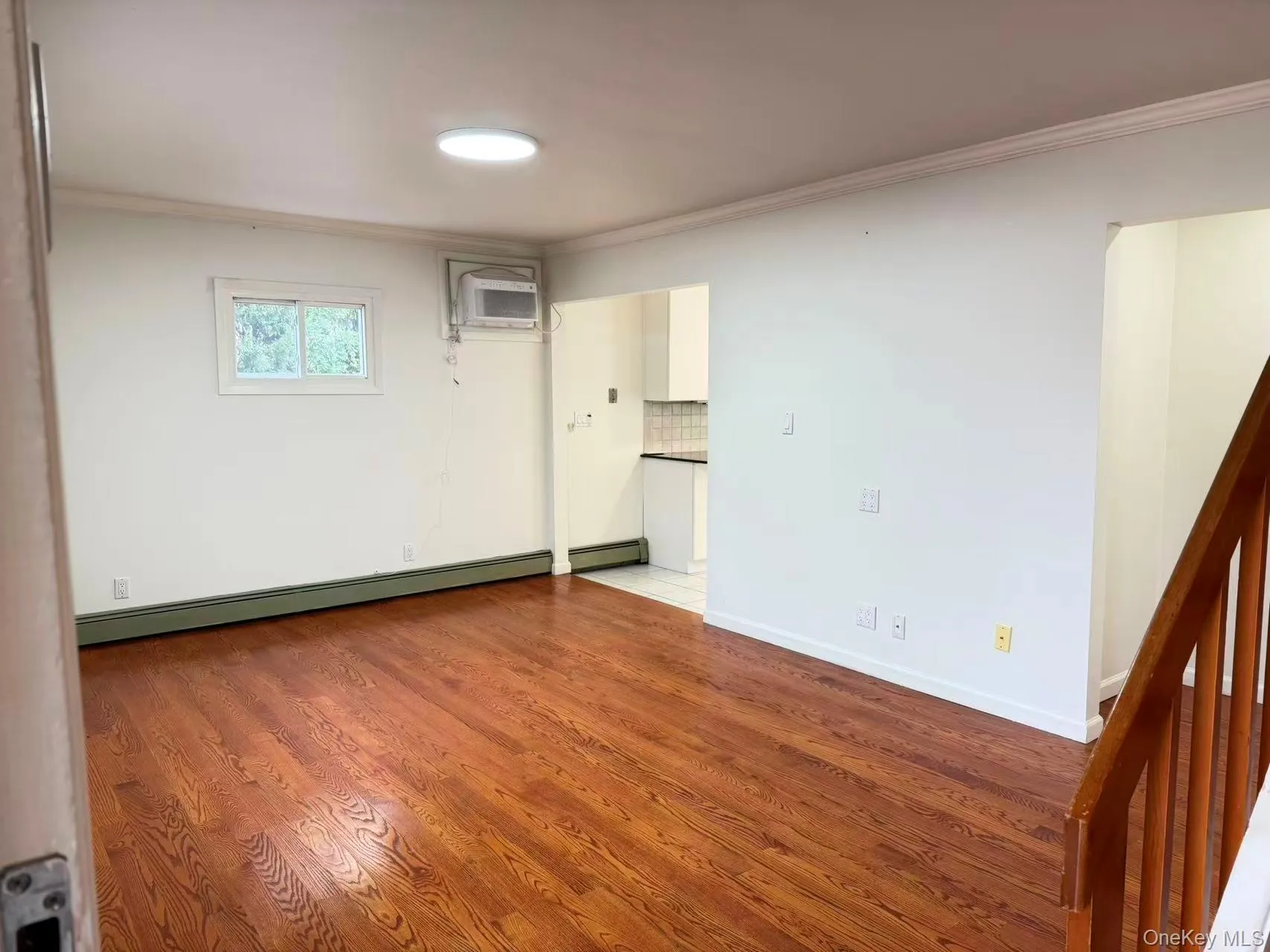 Spare room featuring crown molding, wood finished floors, and baseboard heating Spare room featuring crown molding, wood finished floors, and baseboard heating