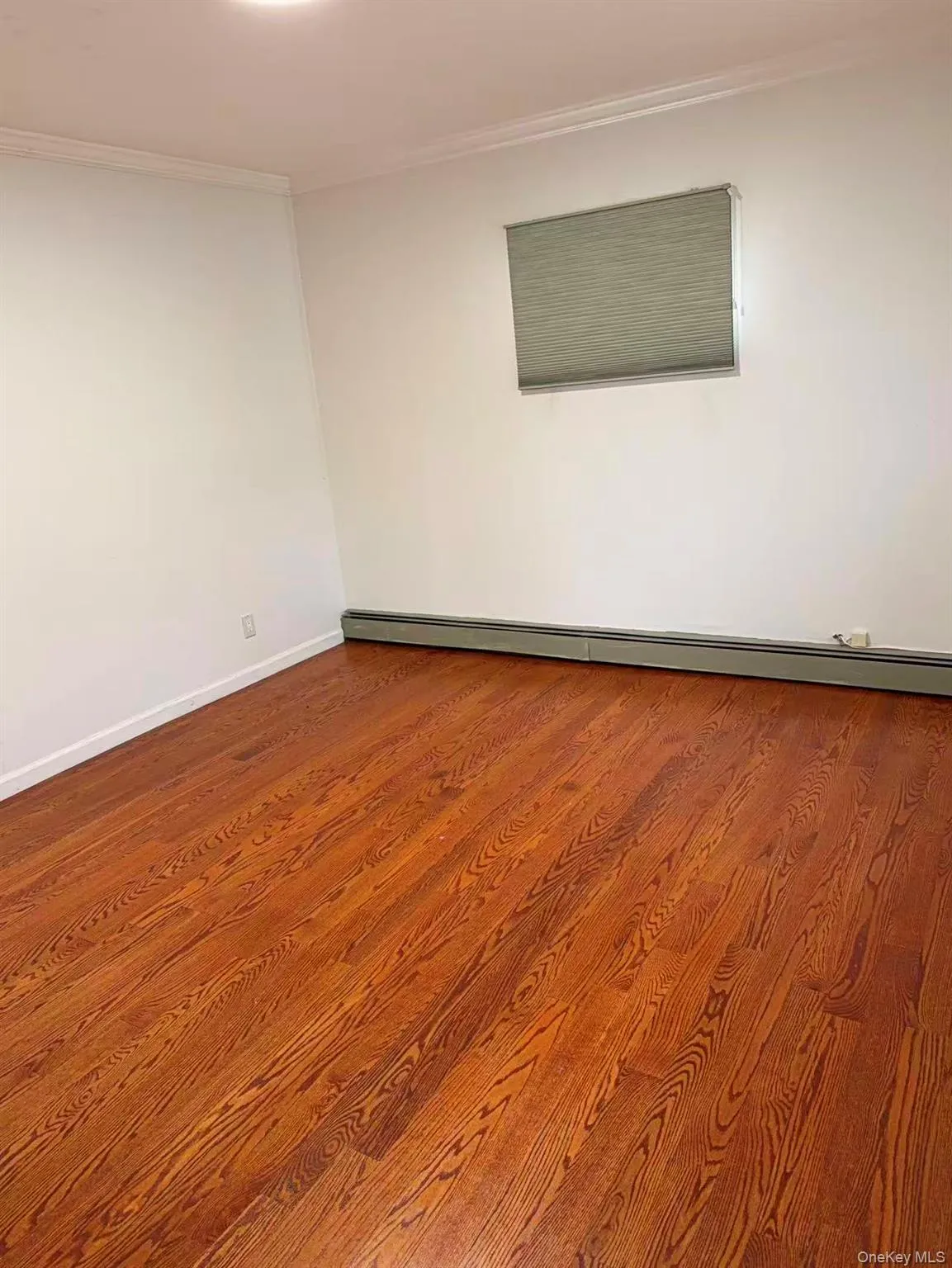 Unfurnished room featuring ornamental molding, a baseboard heating unit, and wood finished floors Unfurnished room featuring ornamental molding, a baseboard heating unit, and wood finished floors