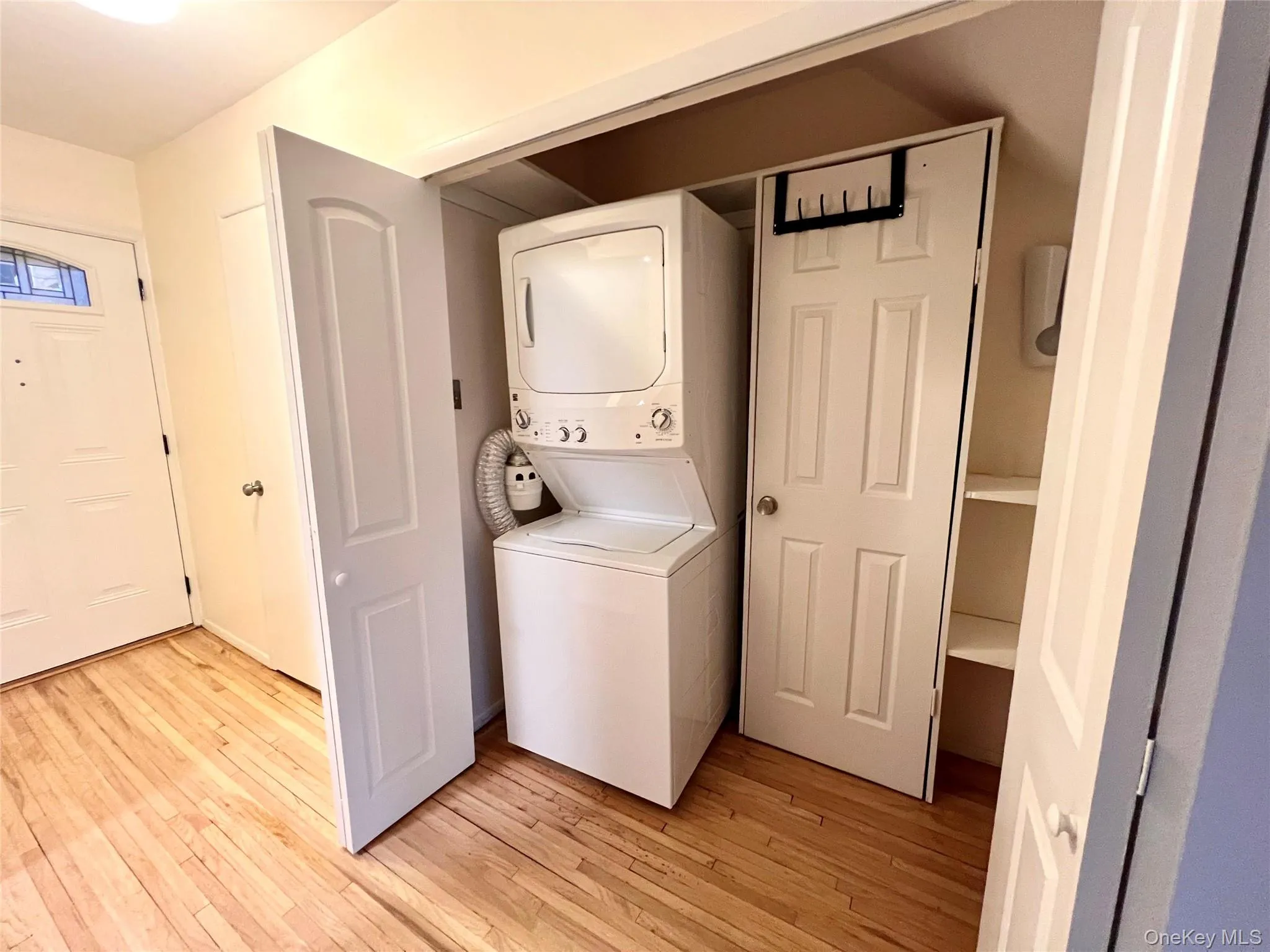 Laundry area with light wood-type flooring and stacked washer and clothes dryer Laundry area with light wood-type flooring and stacked washer and clothes dryer