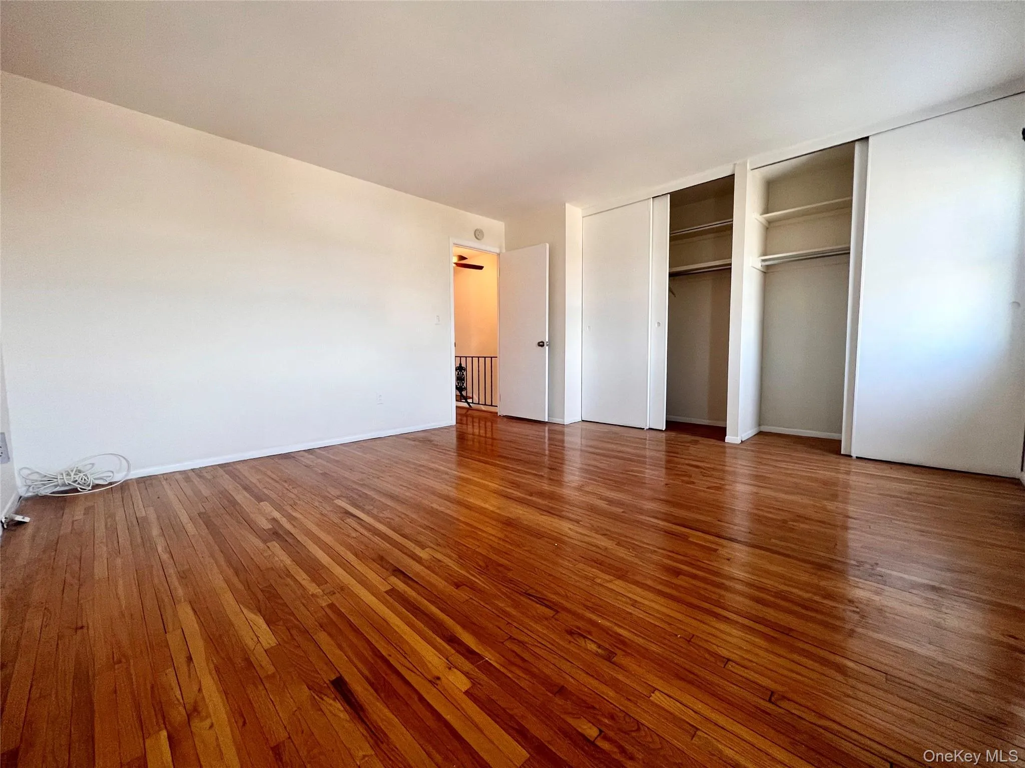 Unfurnished bedroom featuring multiple closets and hardwood / wood-style flooring Unfurnished bedroom featuring multiple closets and hardwood / wood-style flooring