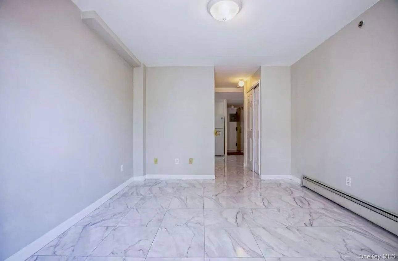 Empty room featuring a baseboard radiator and light marble finish flooring Empty room featuring a baseboard radiator and light marble finish flooring