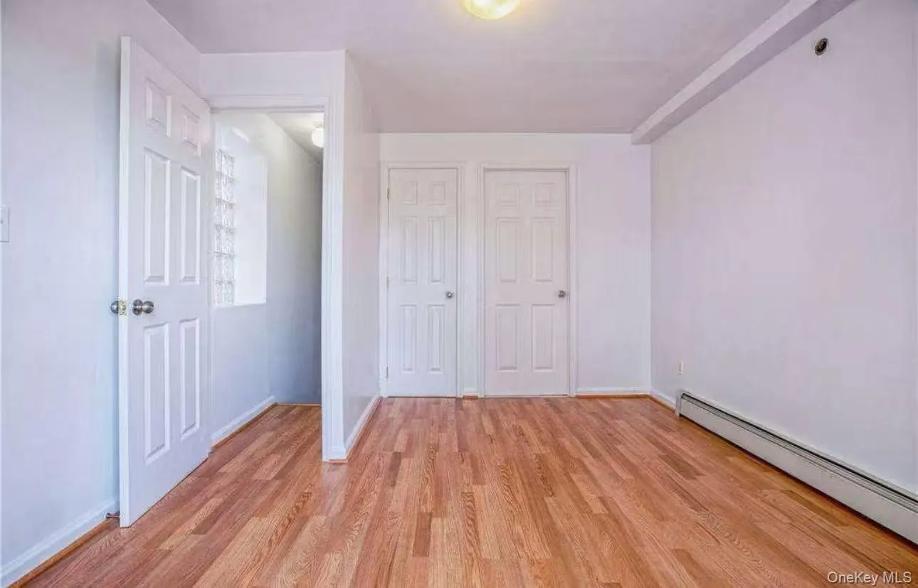 Unfurnished bedroom featuring a baseboard heating unit, light wood-type flooring, and a closet Unfurnished bedroom featuring a baseboard heating unit, light wood-type flooring, and a closet