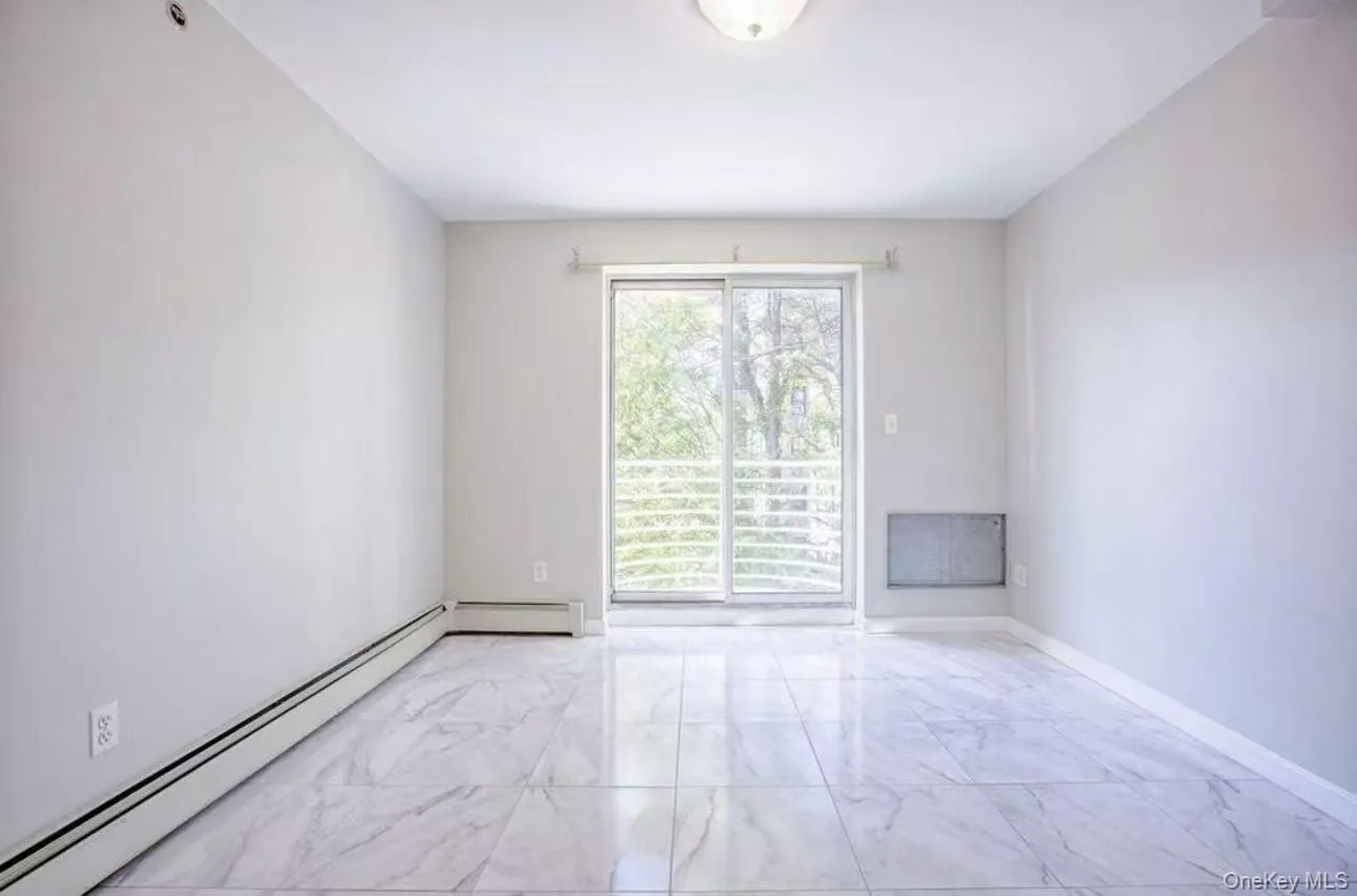 Unfurnished room featuring a baseboard heating unit and light marble finish floors Unfurnished room featuring a baseboard heating unit and light marble finish floors