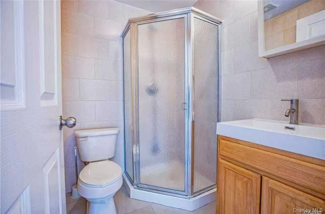 Full bathroom featuring tile walls, a stall shower, vanity, and tile patterned flooring Full bathroom featuring tile walls, a stall shower, vanity, and tile patterned flooring