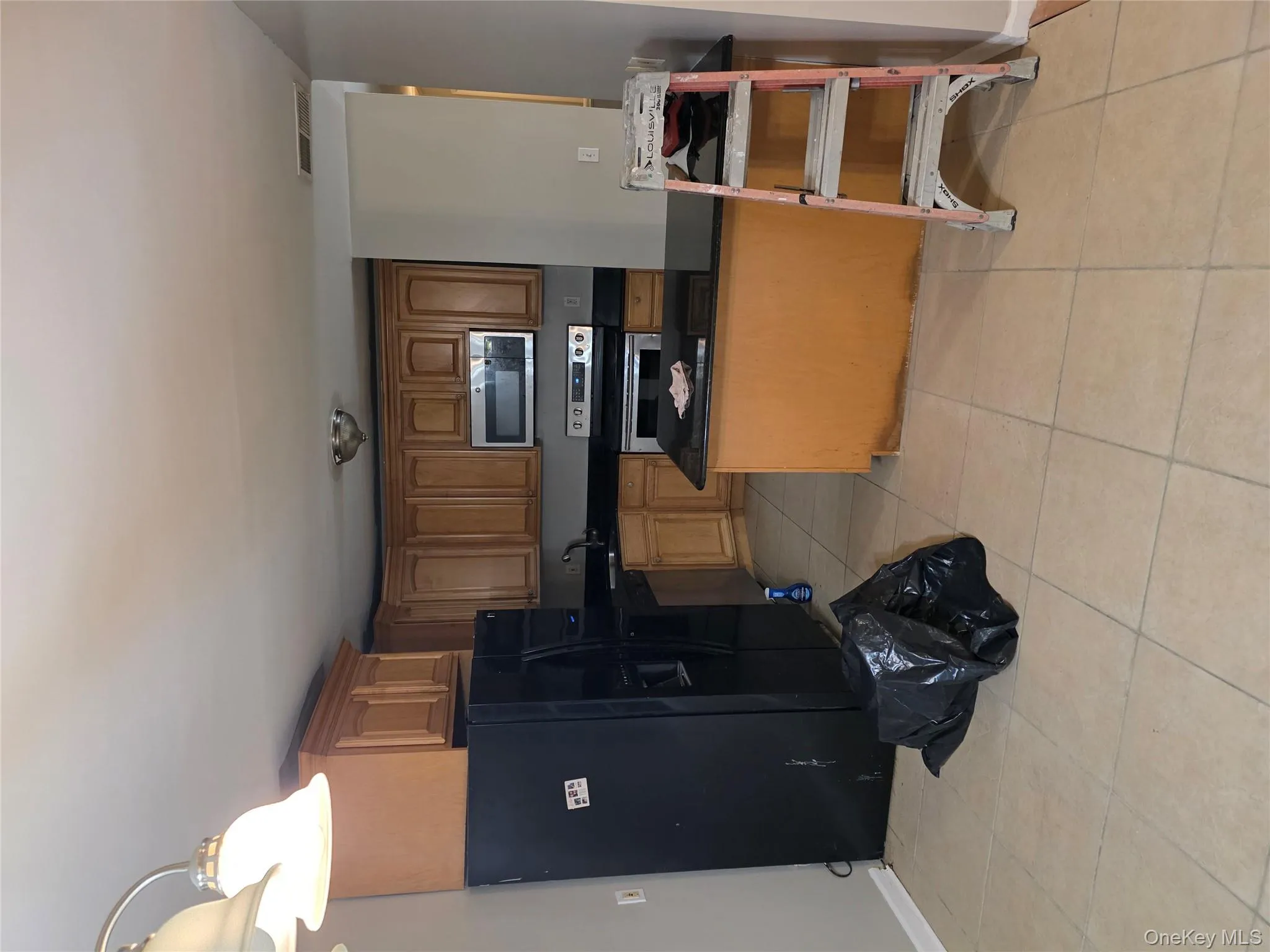 Kitchen featuring stainless steel fridge, range, black microwave, brown cabinetry, and a peninsula Kitchen featuring stainless steel fridge, range, black microwave, brown cabinetry, and a peninsula