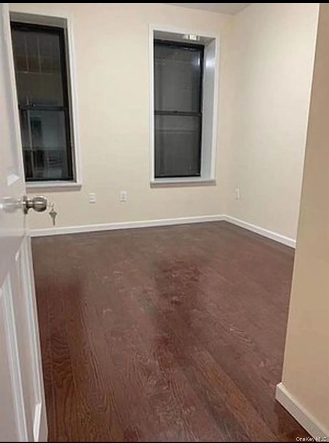 Unfurnished room featuring baseboards and dark wood-style floors Unfurnished room featuring baseboards and dark wood-style floors