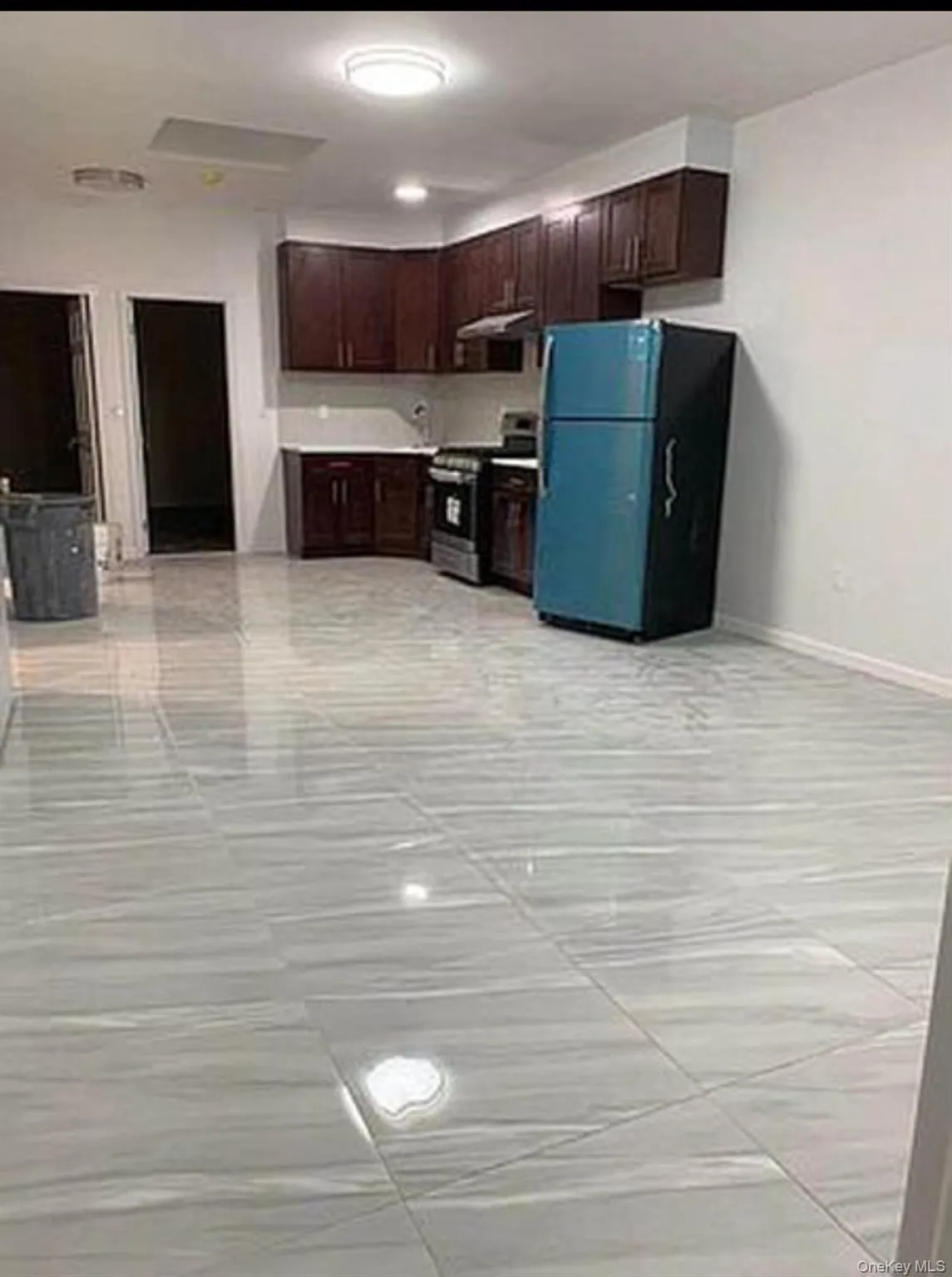 Kitchen featuring dark brown cabinetry, freestanding refrigerator, stainless steel range oven, and light countertops Kitchen featuring dark brown cabinetry, freestanding refrigerator, stainless steel range oven, and light countertops