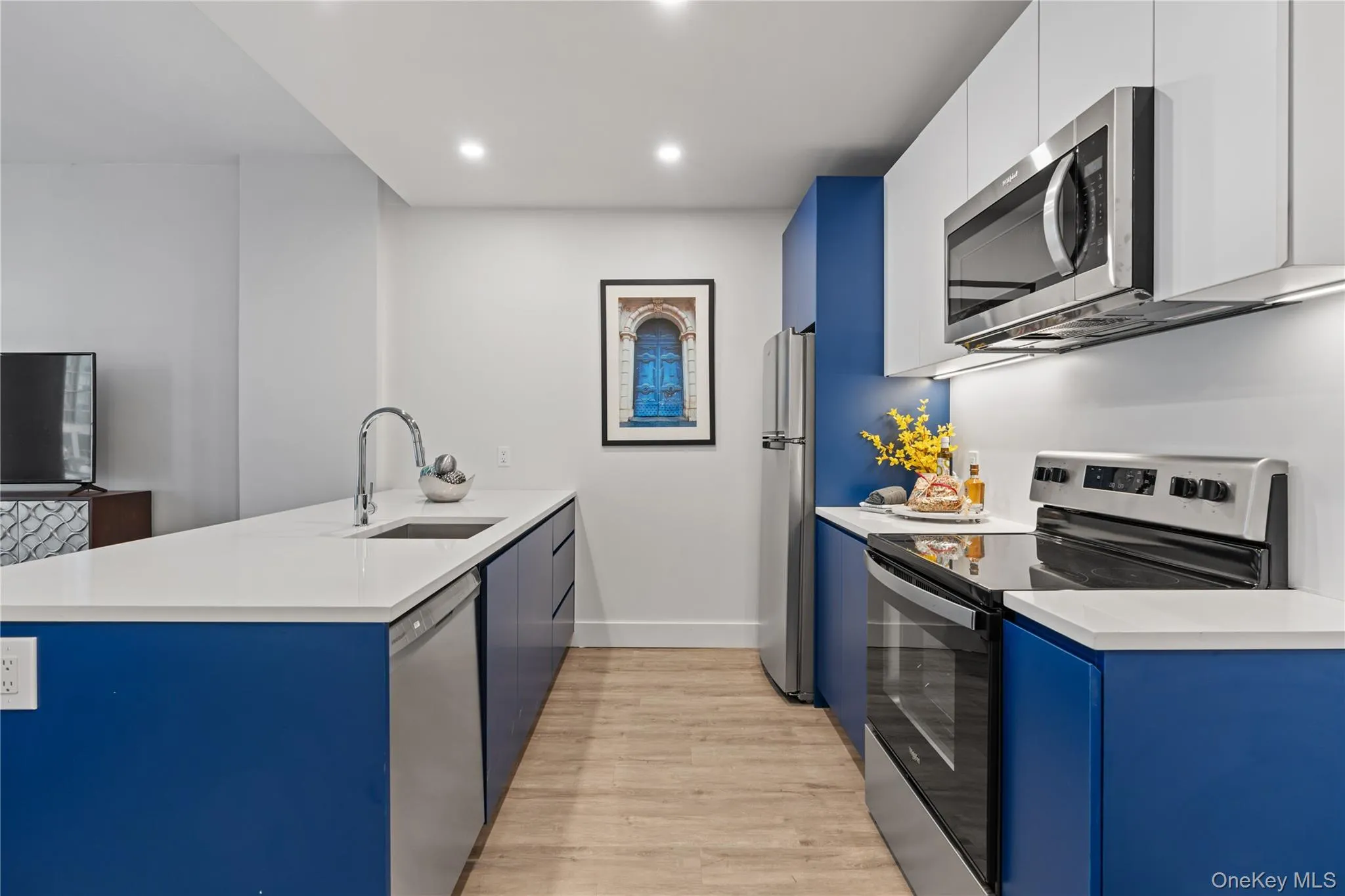 Kitchen with stainless steel appliances, blue cabinetry, a peninsula, modern cabinets, and recessed lighting Kitchen with stainless steel appliances, blue cabinetry, a peninsula, modern cabinets, and recessed lighting