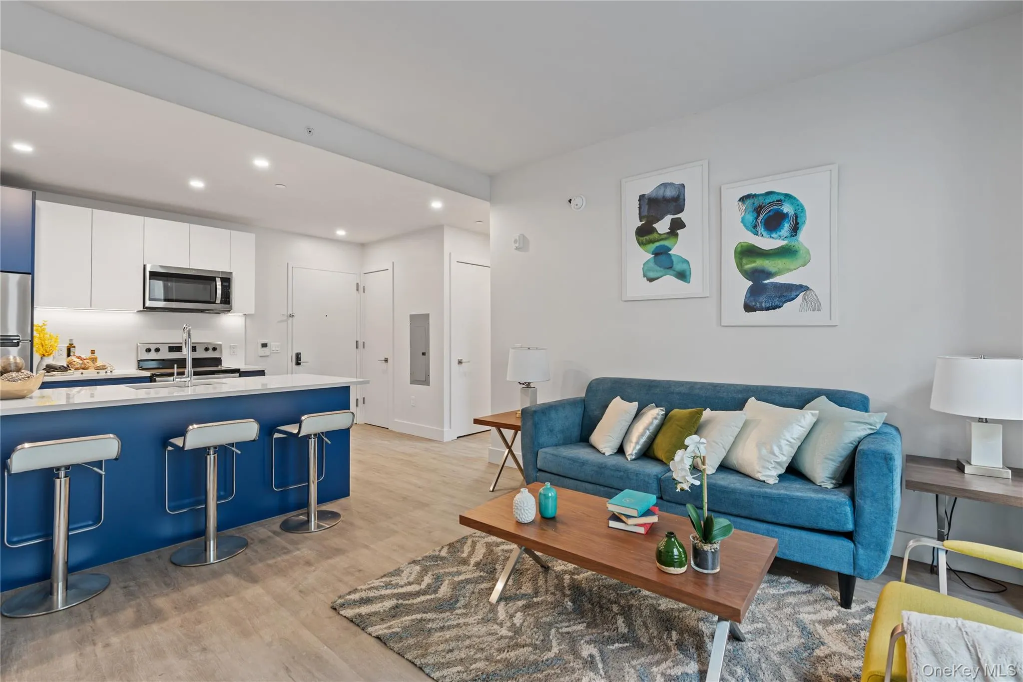 Living area with recessed lighting, light wood-style flooring, and electric panel Living area with recessed lighting, light wood-style flooring, and electric panel
