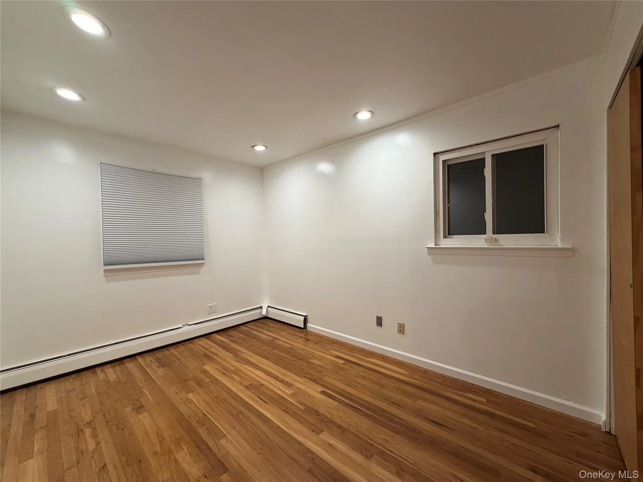 Spare room featuring hardwood / wood-style floors, recessed lighting, and a baseboard heating unit Spare room featuring hardwood / wood-style floors, recessed lighting, and a baseboard heating unit