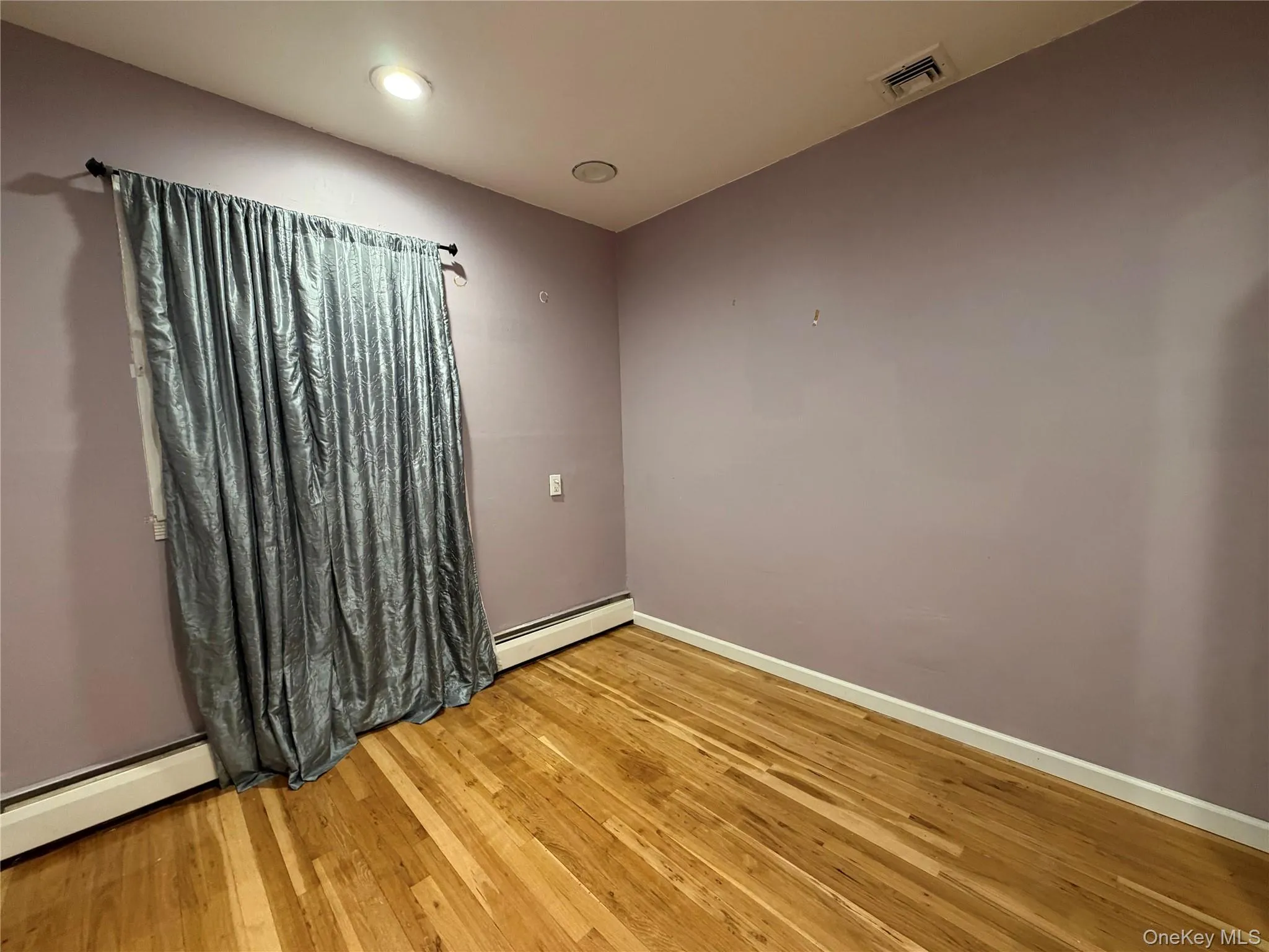 Empty room with a baseboard radiator, light wood-style flooring, a baseboard heating unit, and recessed lighting Empty room with a baseboard radiator, light wood-style flooring, a baseboard heating unit, and recessed lighting