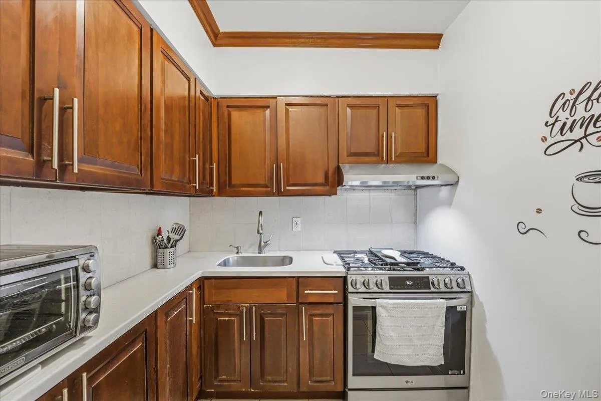 Kitchen featuring stainless steel range with gas cooktop, under cabinet range hood, and tasteful backsplash Kitchen featuring stainless steel range with gas cooktop, under cabinet range hood, and tasteful backsplash