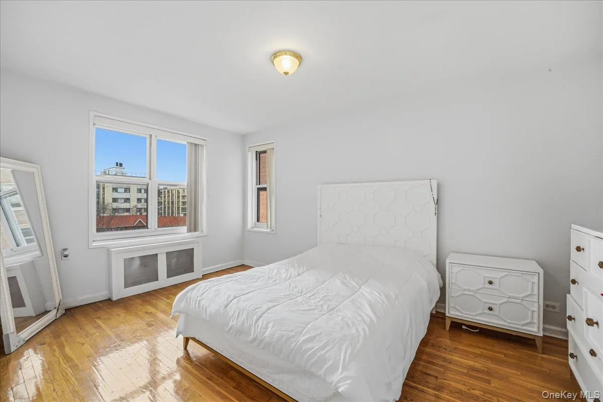 Bedroom featuring radiator heating unit and hardwood / wood-style floors Bedroom featuring radiator heating unit and hardwood / wood-style floors