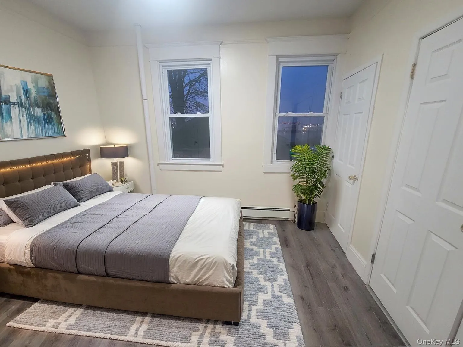 Bedroom with wood finished floors and a baseboard heating unit Bedroom with wood finished floors and a baseboard heating unit