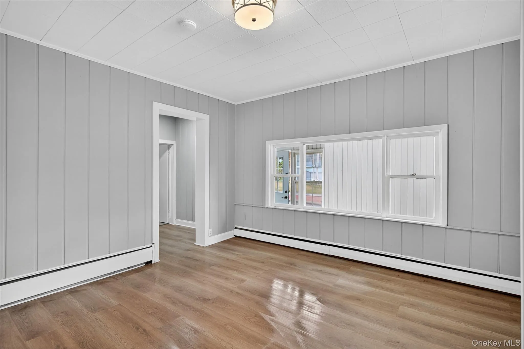 Unfurnished room with a baseboard heating unit and light wood finished floors Unfurnished room with a baseboard heating unit and light wood finished floors