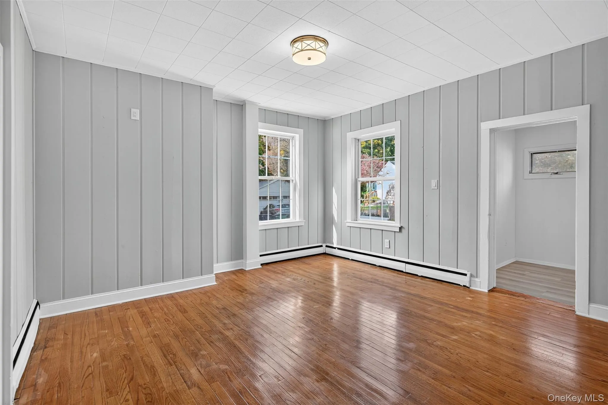 Empty room featuring a baseboard heating unit and hardwood / wood-style floors Empty room featuring a baseboard heating unit and hardwood / wood-style floors