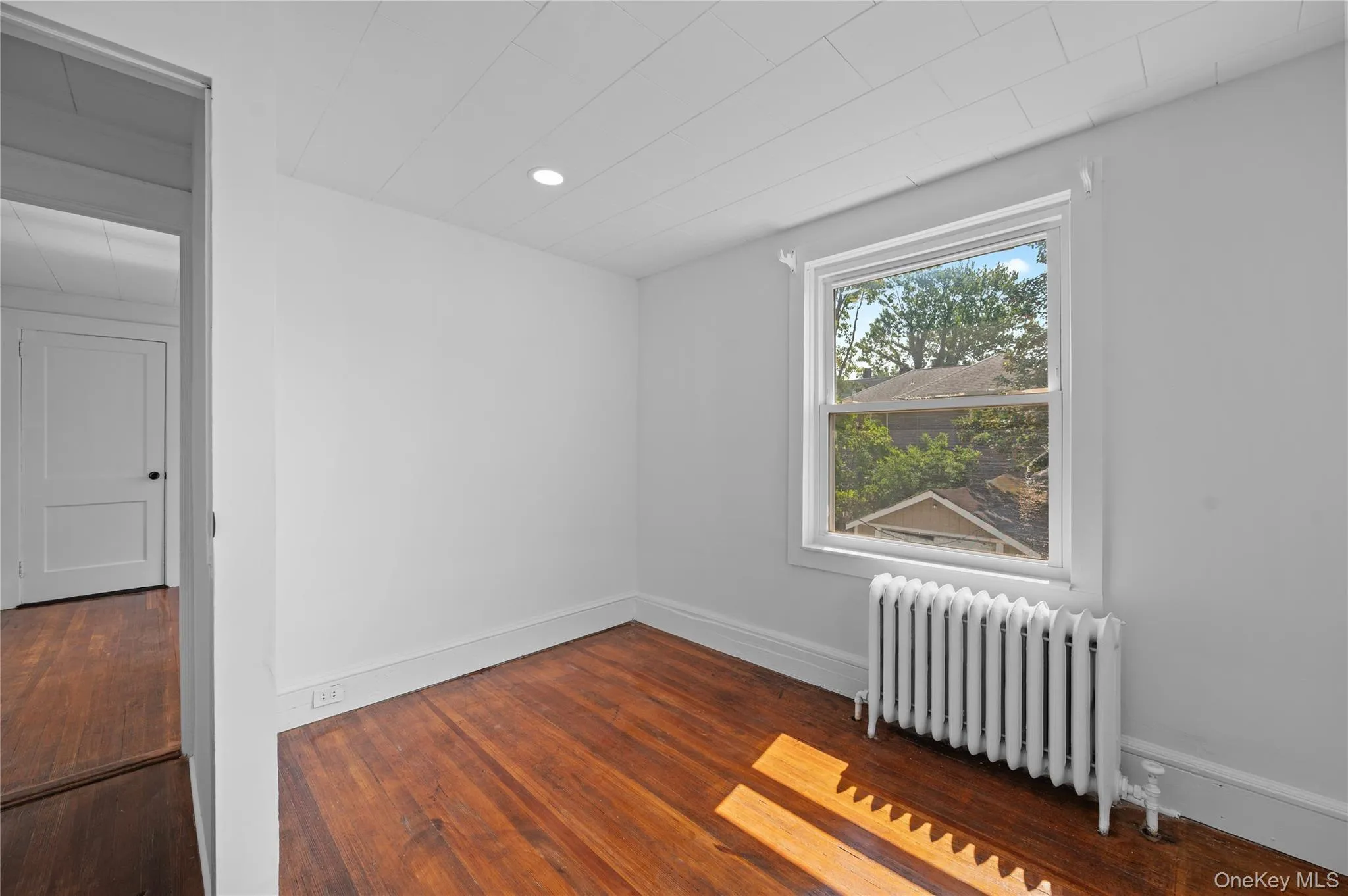 Empty room featuring radiator, dark wood finished floors, and recessed lighting Empty room featuring radiator, dark wood finished floors, and recessed lighting