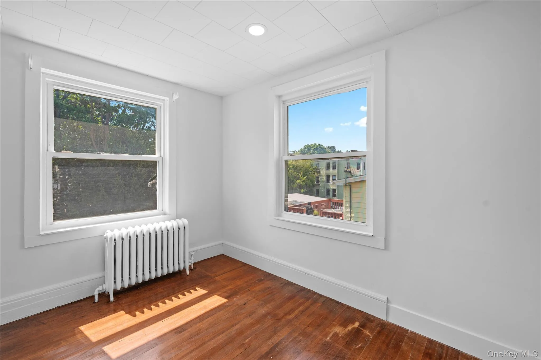 Spare room featuring radiator heating unit and dark wood finished floors Spare room featuring radiator heating unit and dark wood finished floors