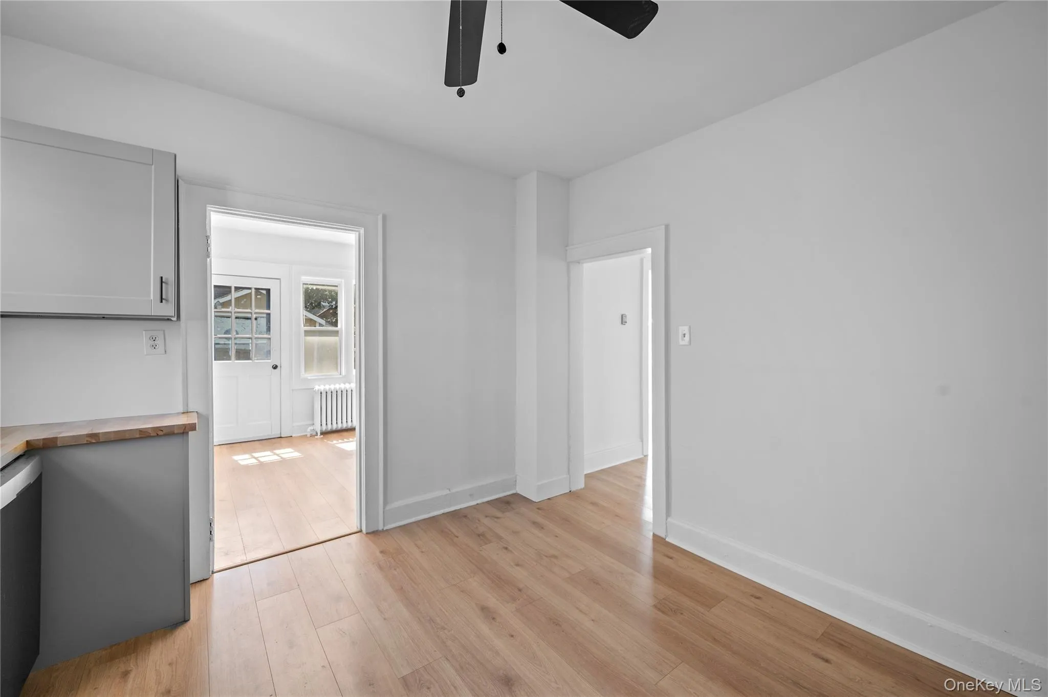 Unfurnished room featuring light wood-style floors, a ceiling fan, and radiator Unfurnished room featuring light wood-style floors, a ceiling fan, and radiator