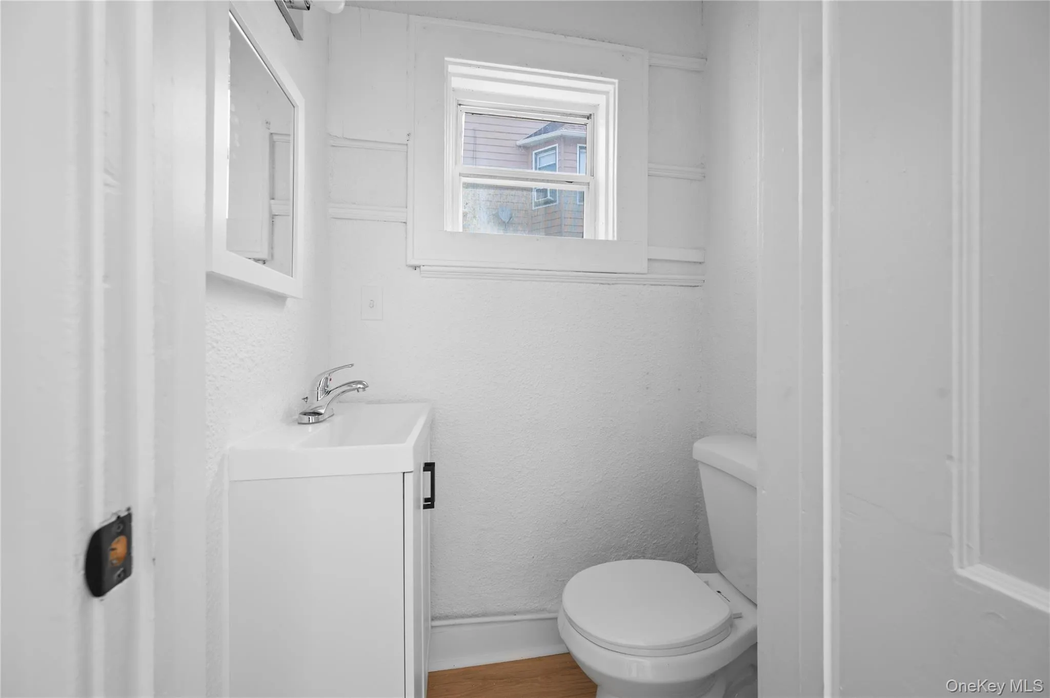 Half bathroom featuring vanity and a textured wall Half bathroom featuring vanity and a textured wall
