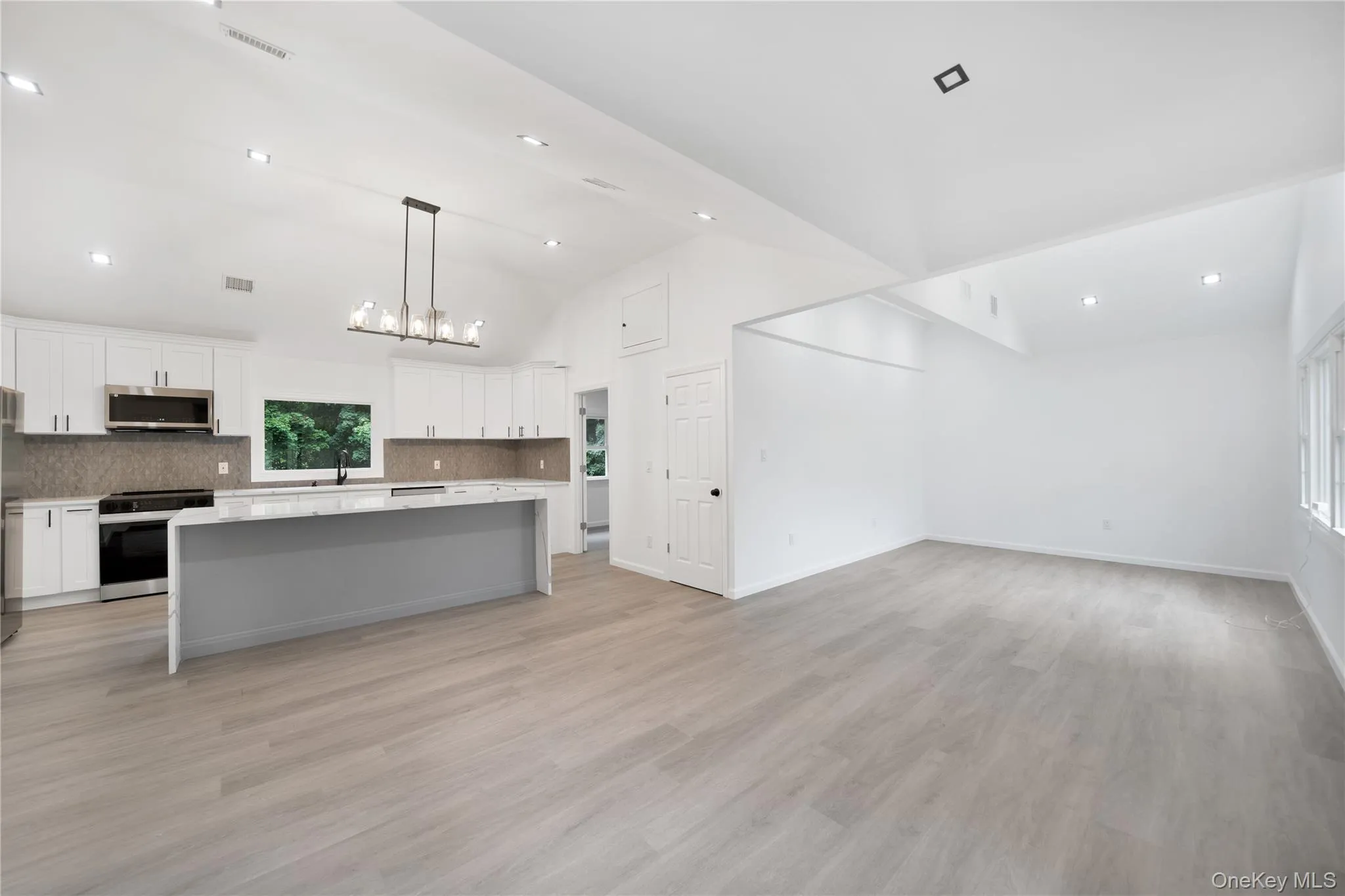 Kitchen featuring a kitchen island, white cabinets, hanging light fixtures, open floor plan, and recessed lighting Kitchen featuring a kitchen island, white cabinets, hanging light fixtures, open floor plan, and recessed lighting