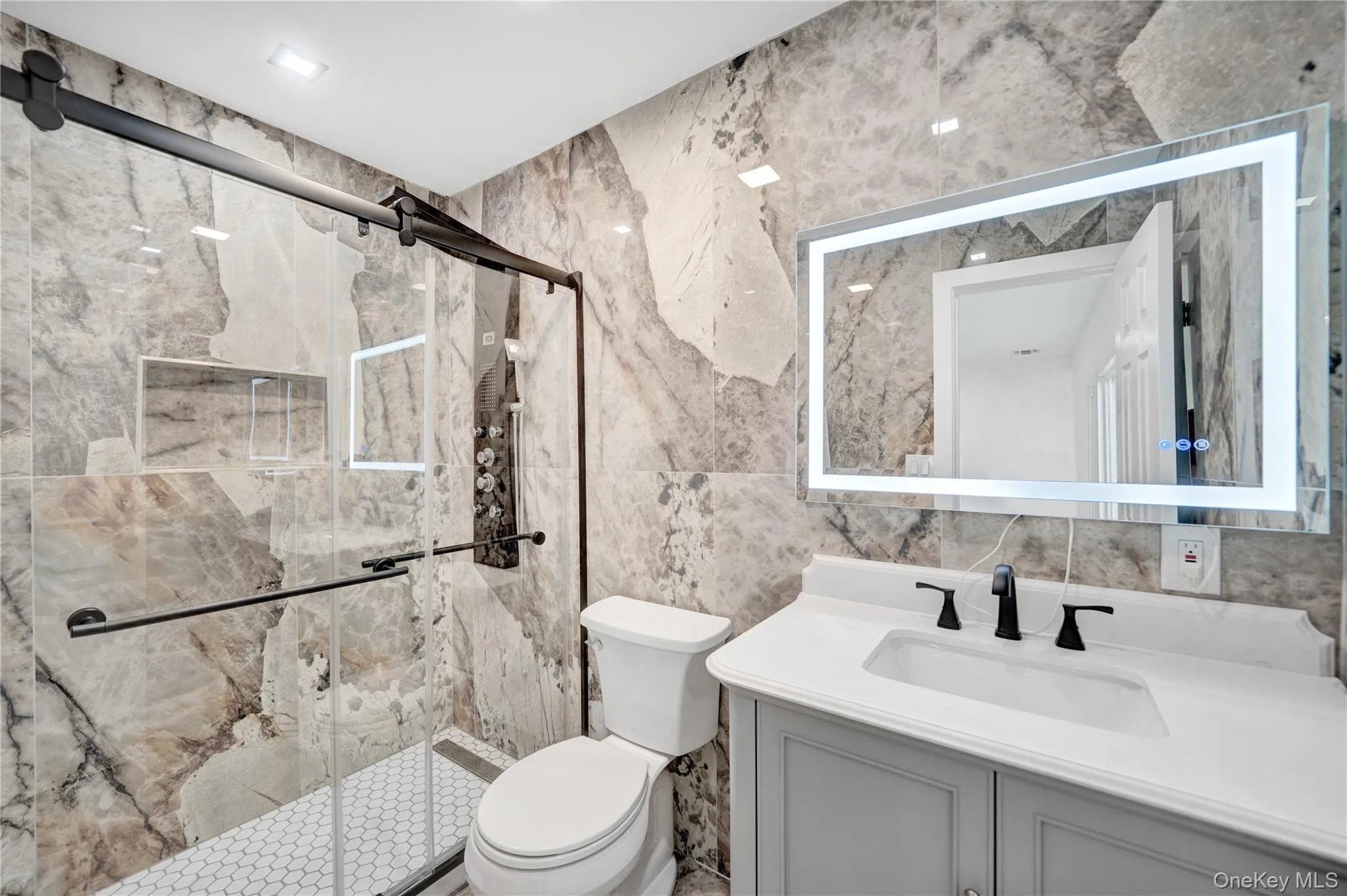 Full bath with tile walls, vanity, a marble finish shower, and recessed lighting Full bath with tile walls, vanity, a marble finish shower, and recessed lighting