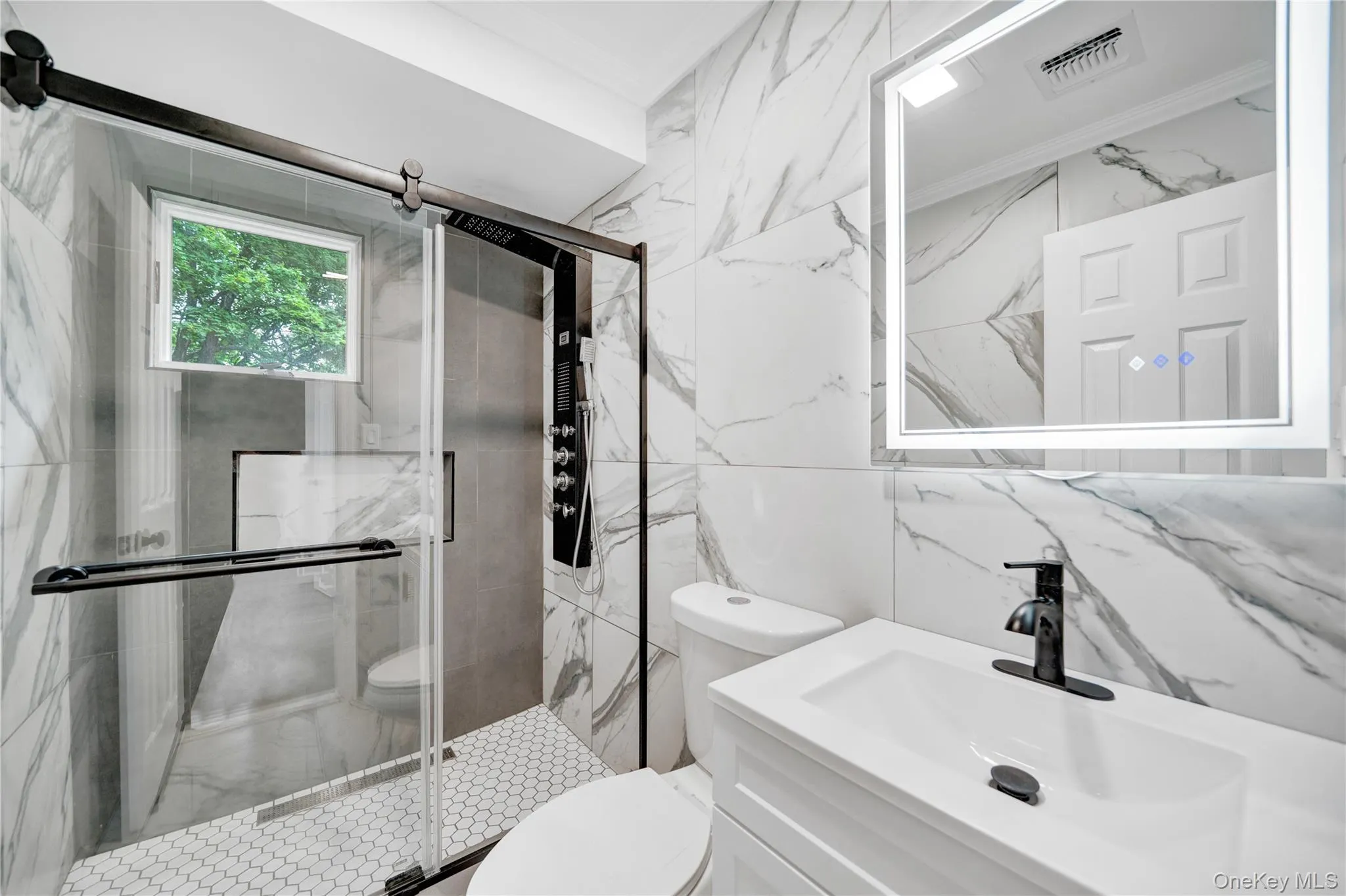Bathroom with vanity, a marble finish shower, crown molding, and tile walls Bathroom with vanity, a marble finish shower, crown molding, and tile walls