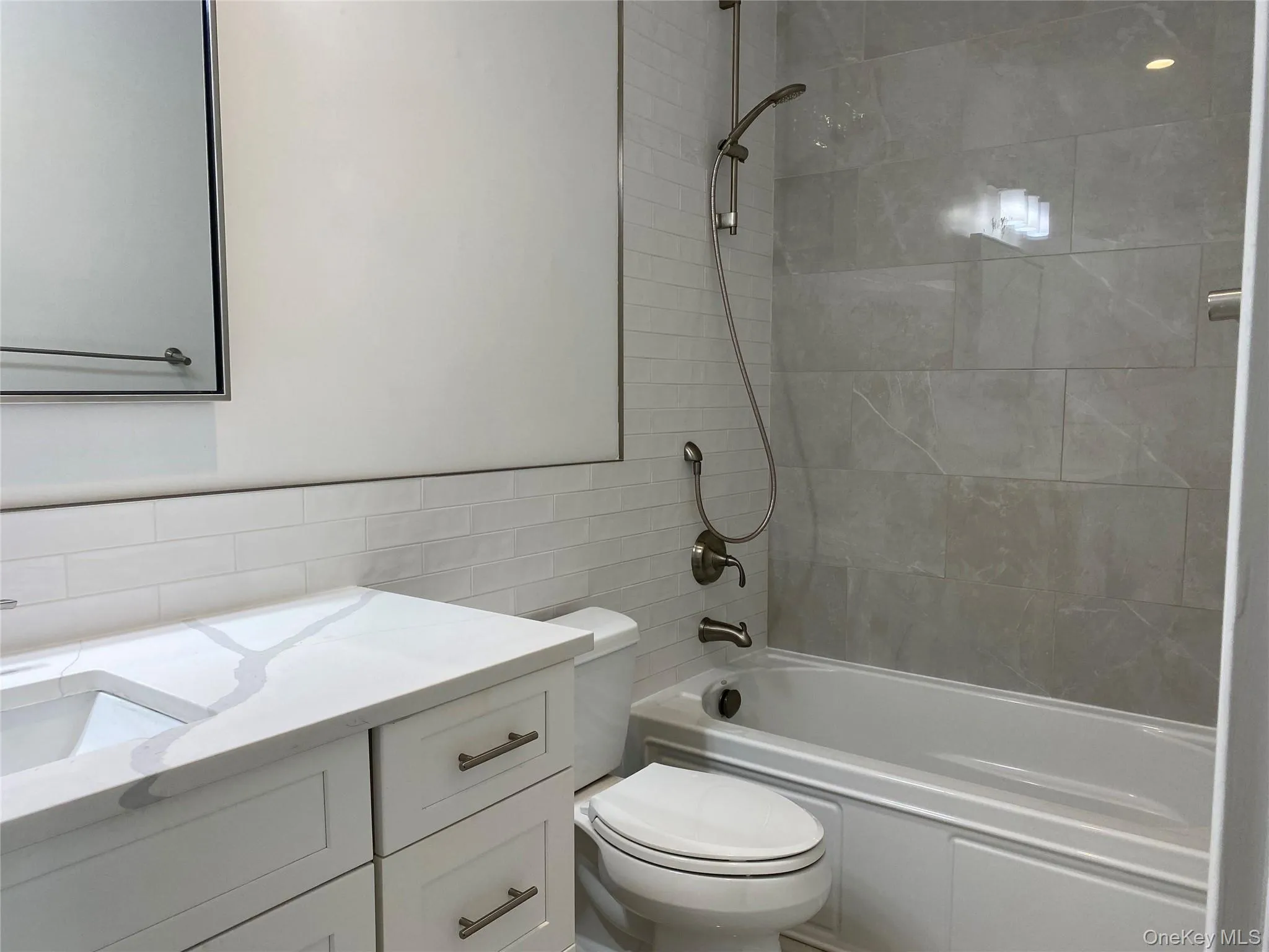 Bathroom featuring tile walls, bathing tub / shower combination, and vanity Bathroom featuring tile walls, bathing tub / shower combination, and vanity