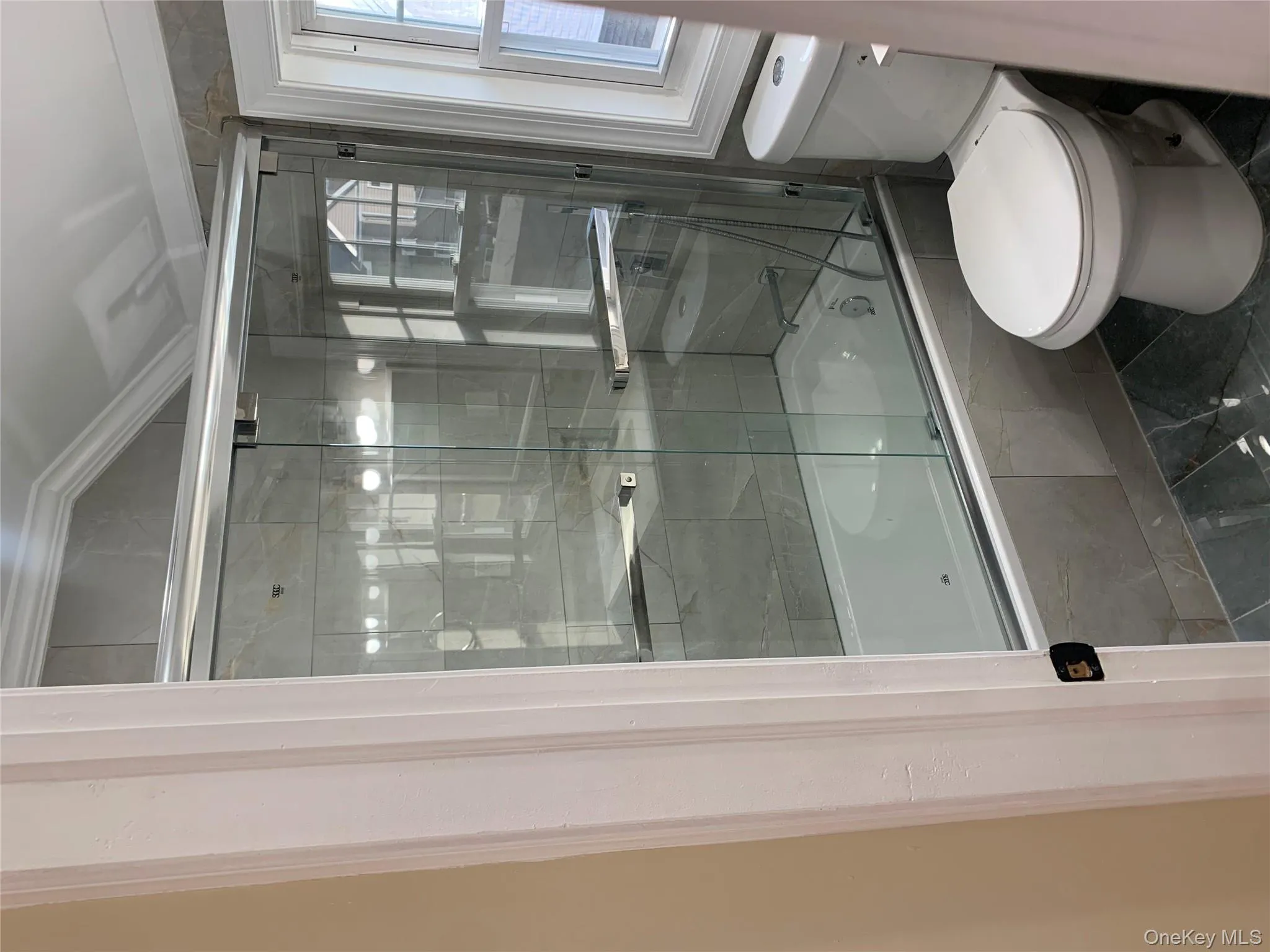 Bathroom with tiled shower / bath combo, vaulted ceiling, and marble look tile flooring Bathroom with tiled shower / bath combo, vaulted ceiling, and marble look tile flooring