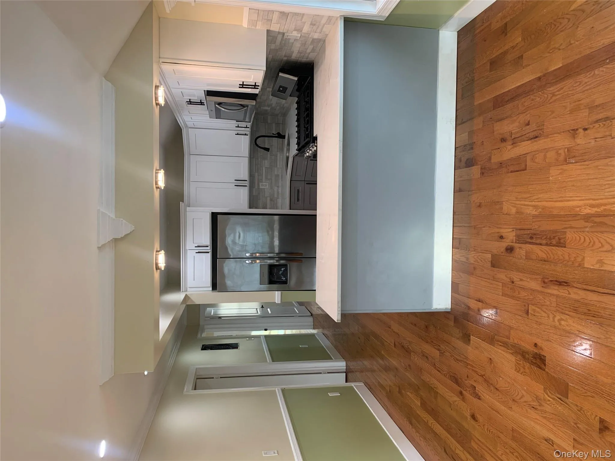 Kitchen with stainless steel fridge, range, dark wood finished floors, a peninsula, and white cabinetry Kitchen with stainless steel fridge, range, dark wood finished floors, a peninsula, and white cabinetry