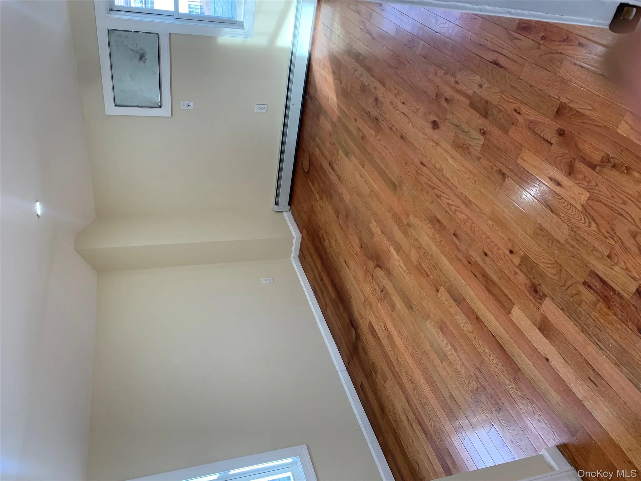 Empty room with healthy amount of natural light, wood-type flooring, and baseboard heating Empty room with healthy amount of natural light, wood-type flooring, and baseboard heating