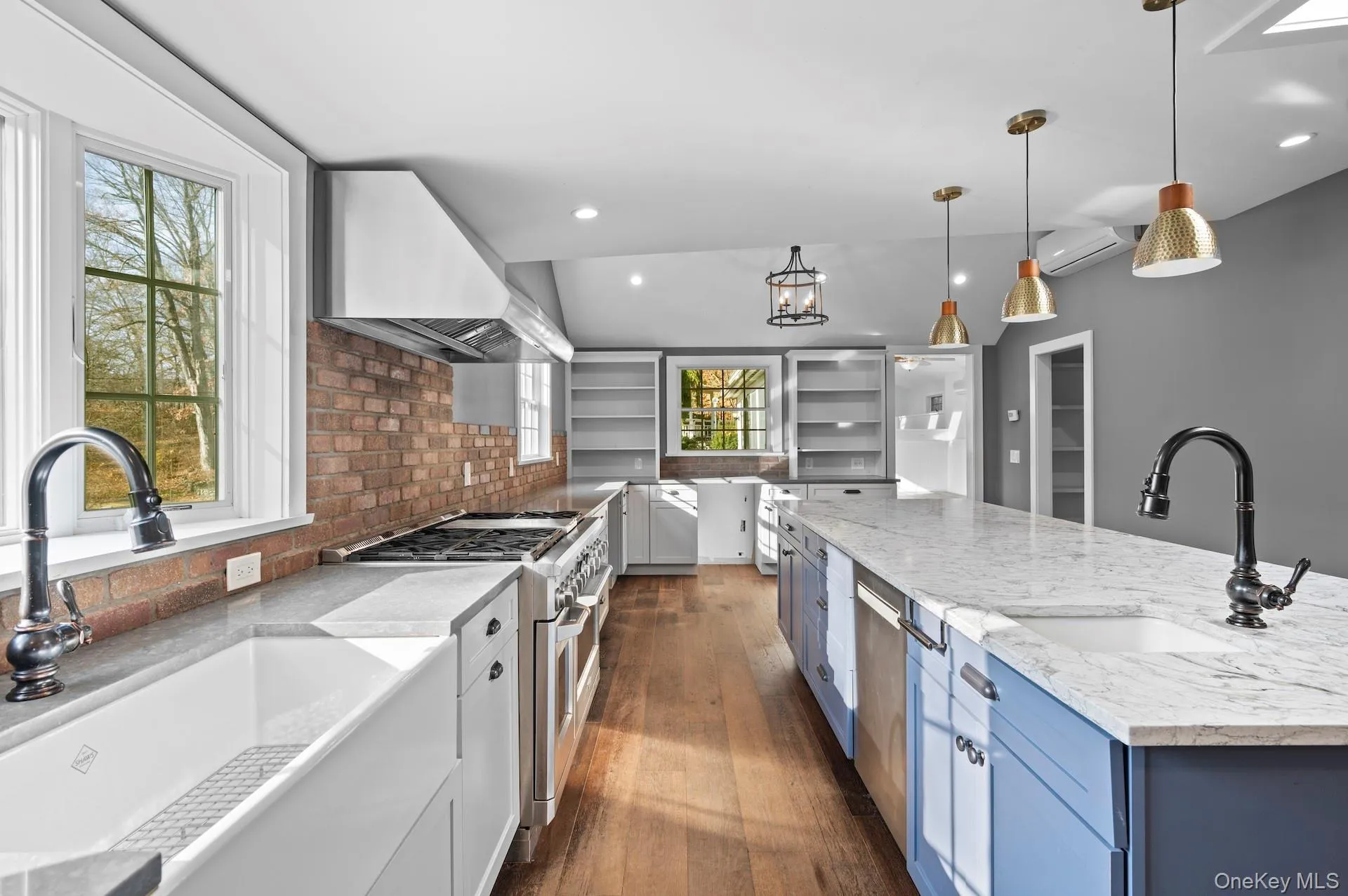 Kitchen featuring light stone countertops, hanging light fixtures, dark wood finished floors, stainless steel appliances, and blue cabinetry Kitchen featuring light stone countertops, hanging light fixtures, dark wood finished floors, stainless steel appliances, and blue cabinetry